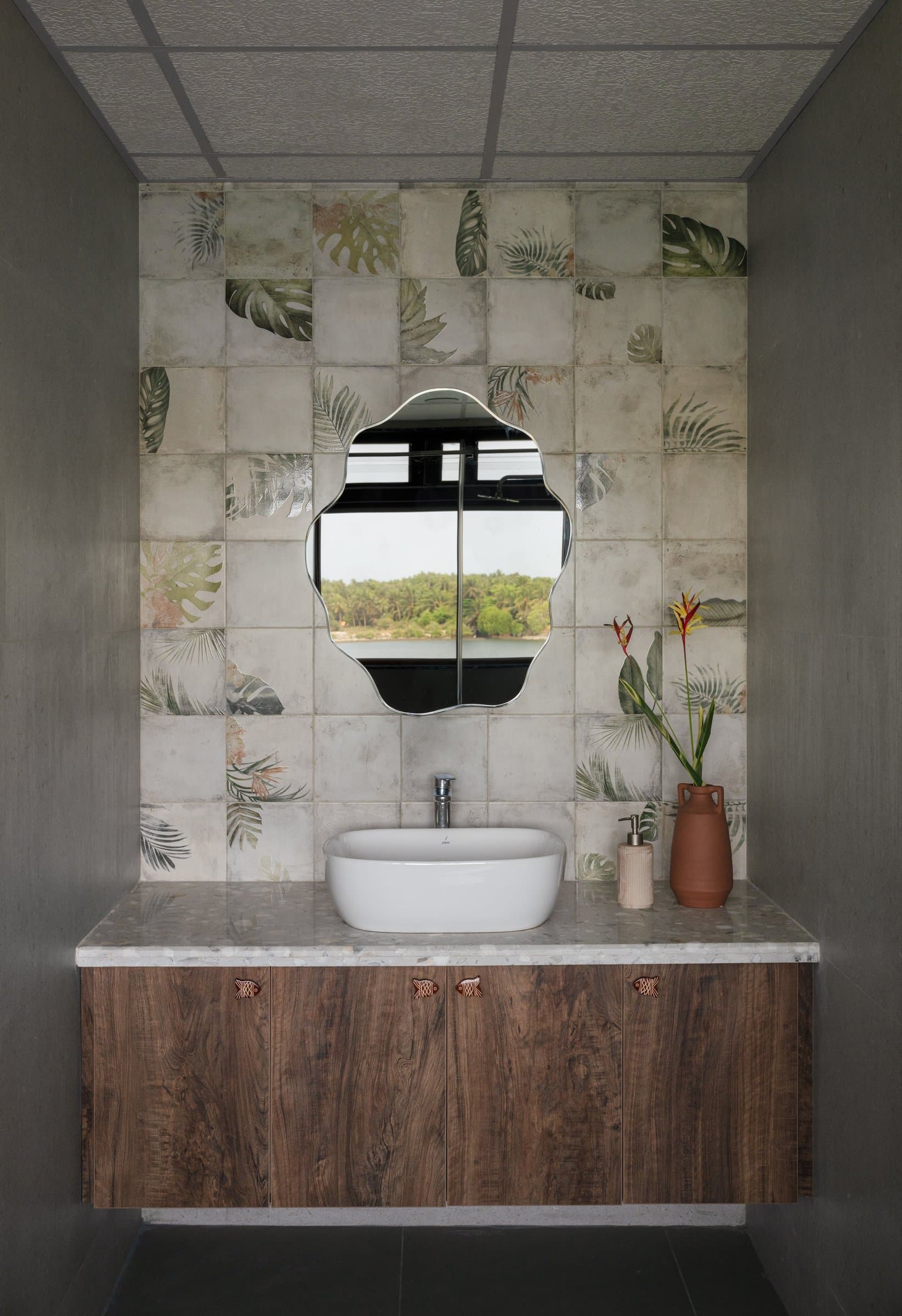 The powder room, where hand-painted monstera tiles and a scalloped mirror lift a small space