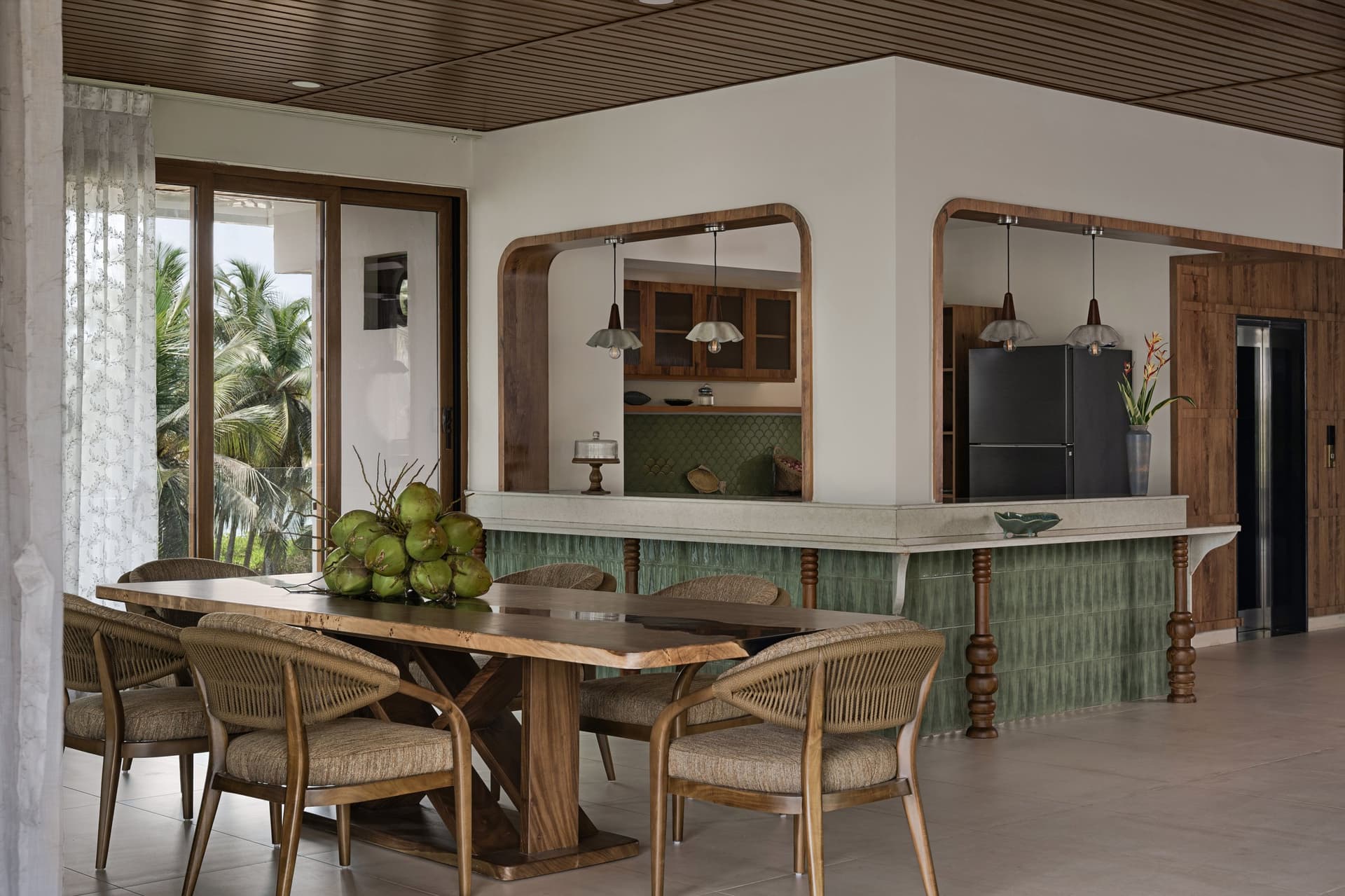 The dining area, where arched openings in warm wood connect to a sage-tiled counter and the river beyond