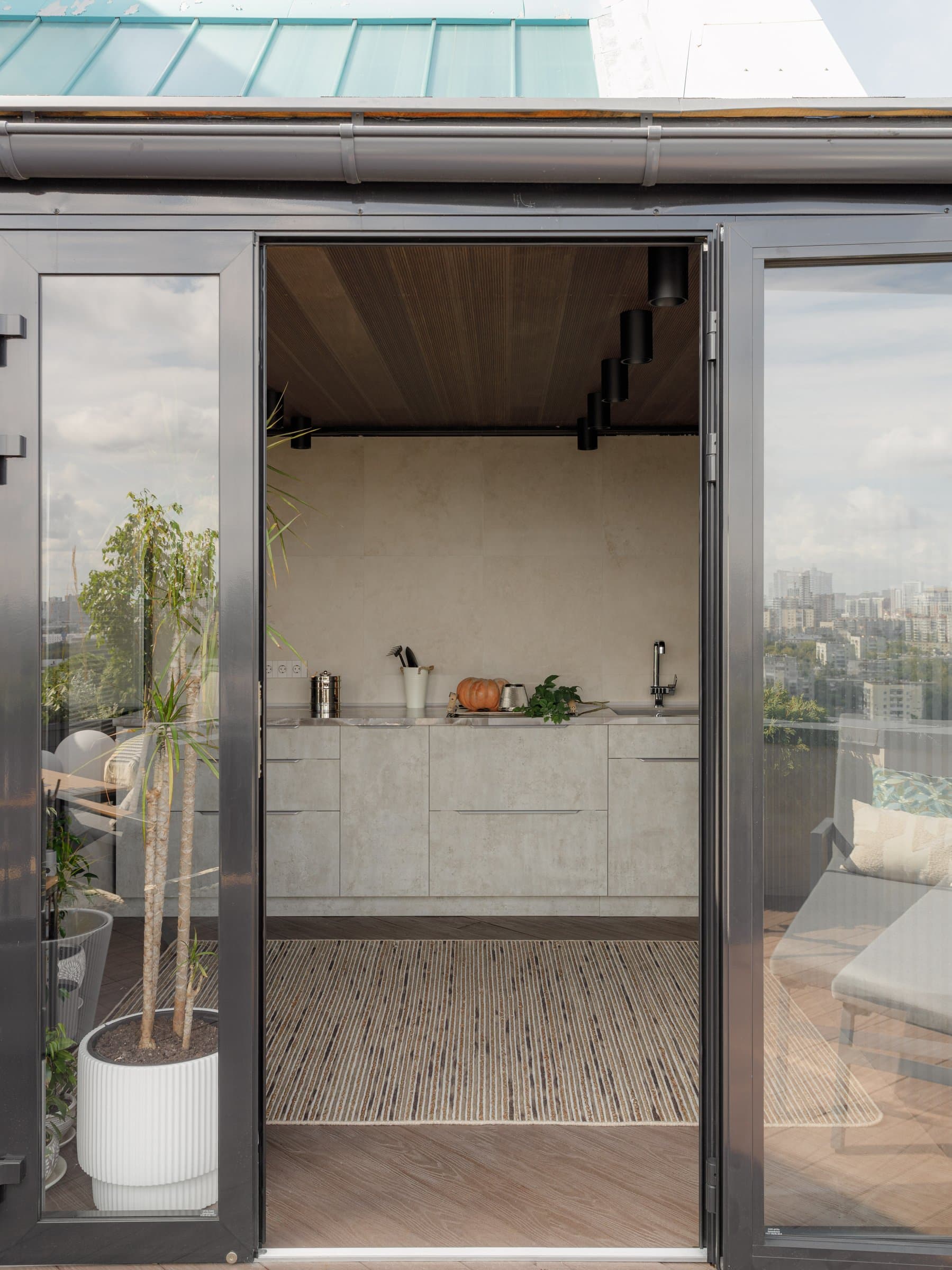 Through the terrace doorway, the summer kitchen appears framed by a warm slatted ceiling