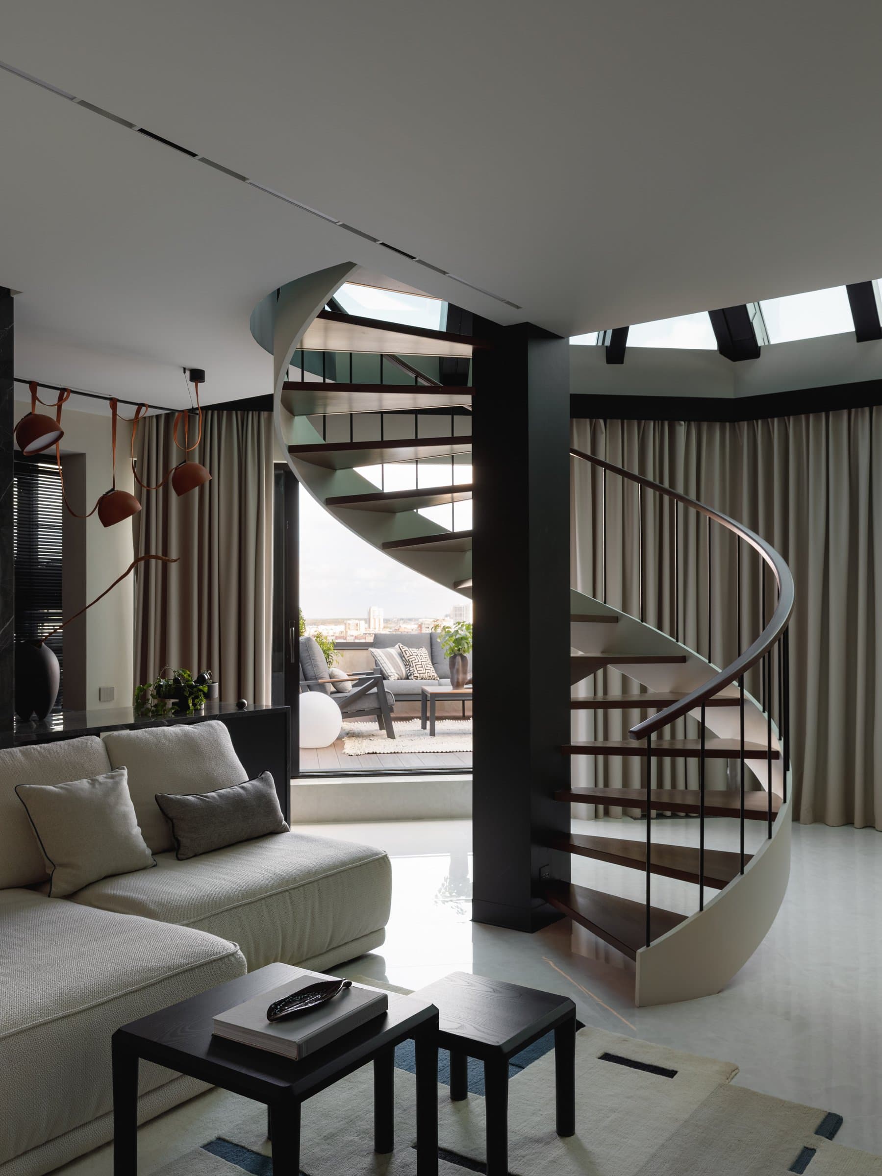 The living room, opening under the stained-glass ceiling toward the terrace, with the spiral stair as sculptural centrepiece