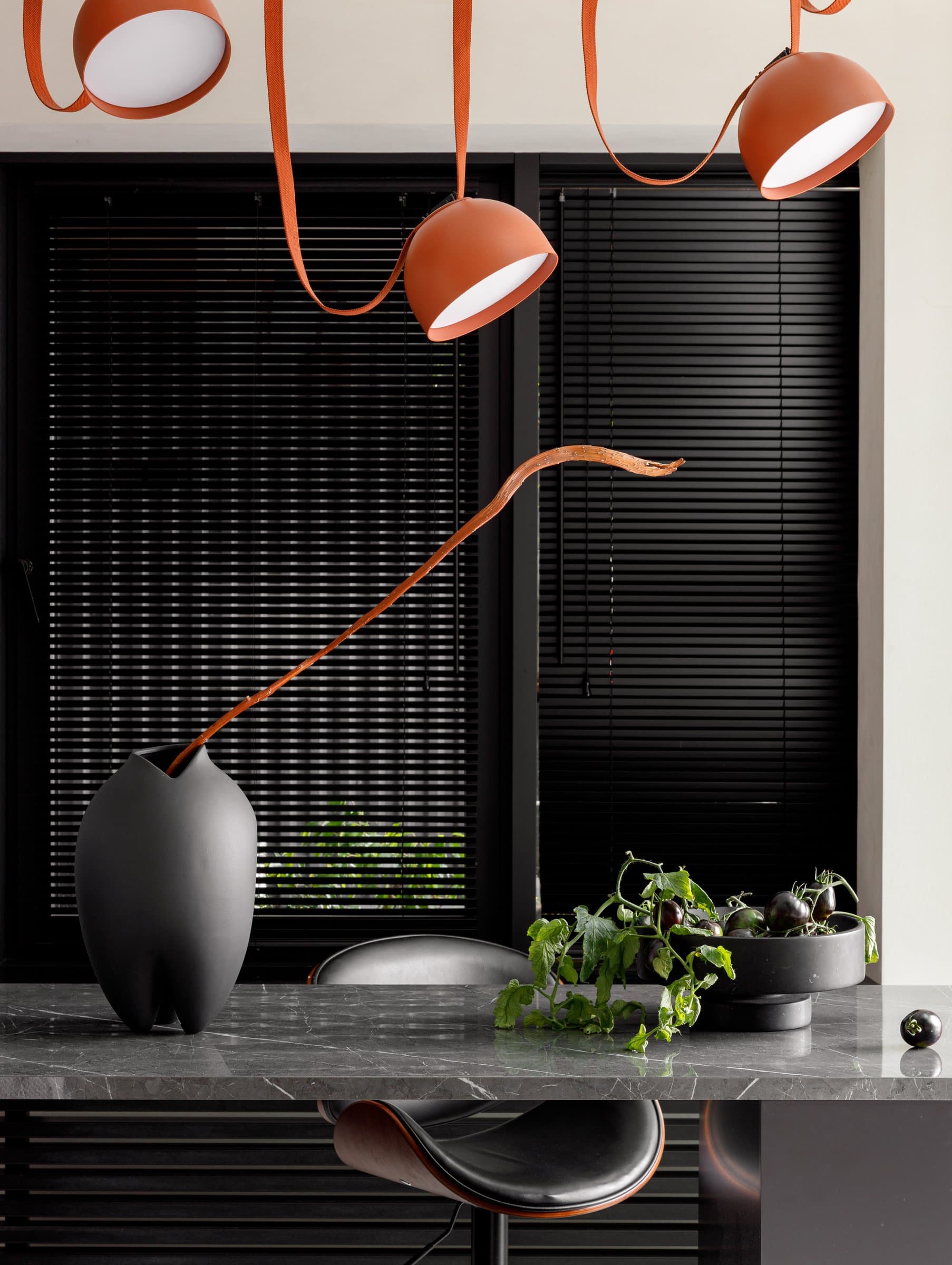 The kitchen island, where terracotta pendants on leather loops set the home's single note of warm colour