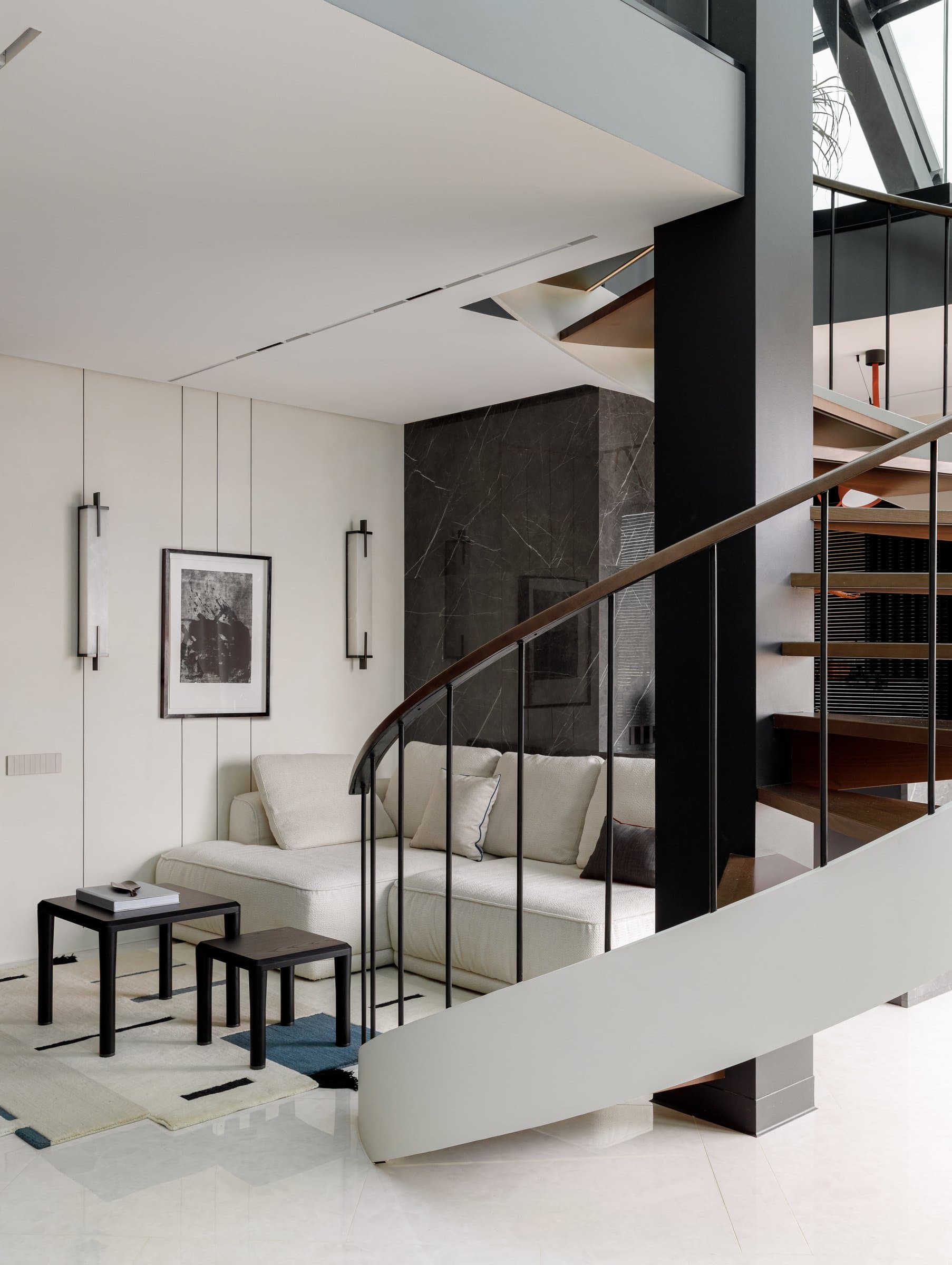 The seating side of the living room, held between panelled walls and the dark marble volume behind the stair