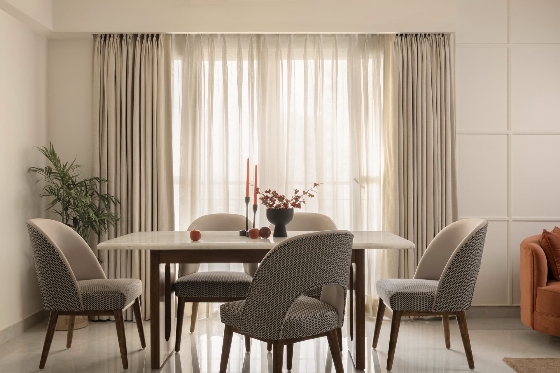 The dining table set against sheer-softened glazing, with chevron-upholstered chairs around a stone top