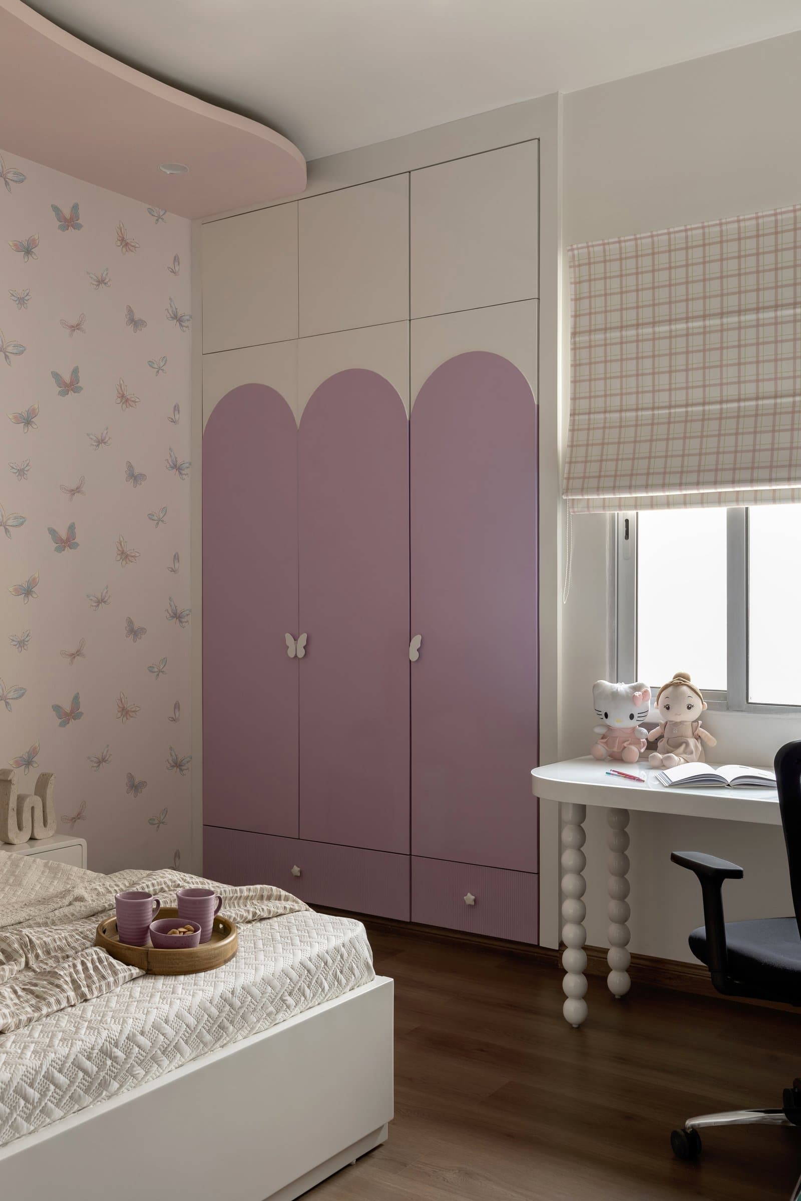 The wardrobe wall of the daughter's room, where three tall mauve arched panels echo the home's recurring threshold motif