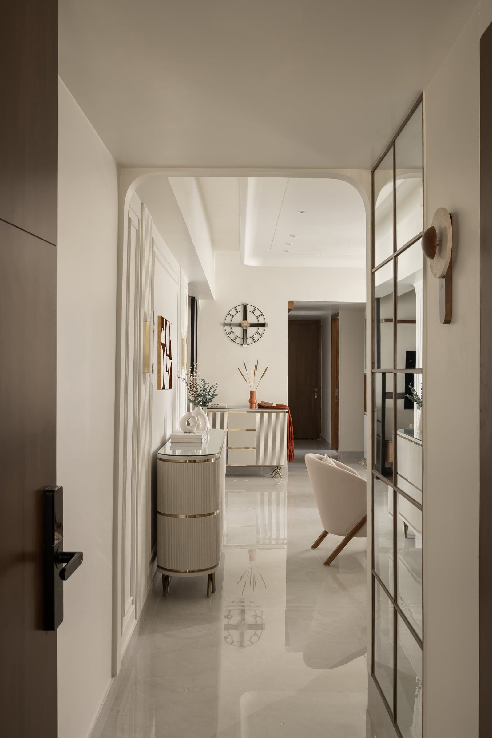 The entry passage, where an arched threshold and a fluted brass-banded console establish the home's material grammar