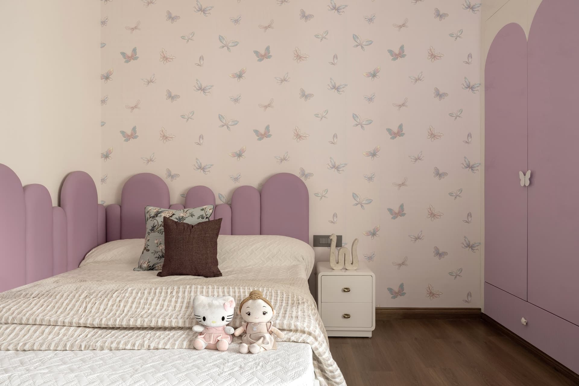 The daughter's room, where a scalloped mauve headboard meets butterfly-print wallpaper