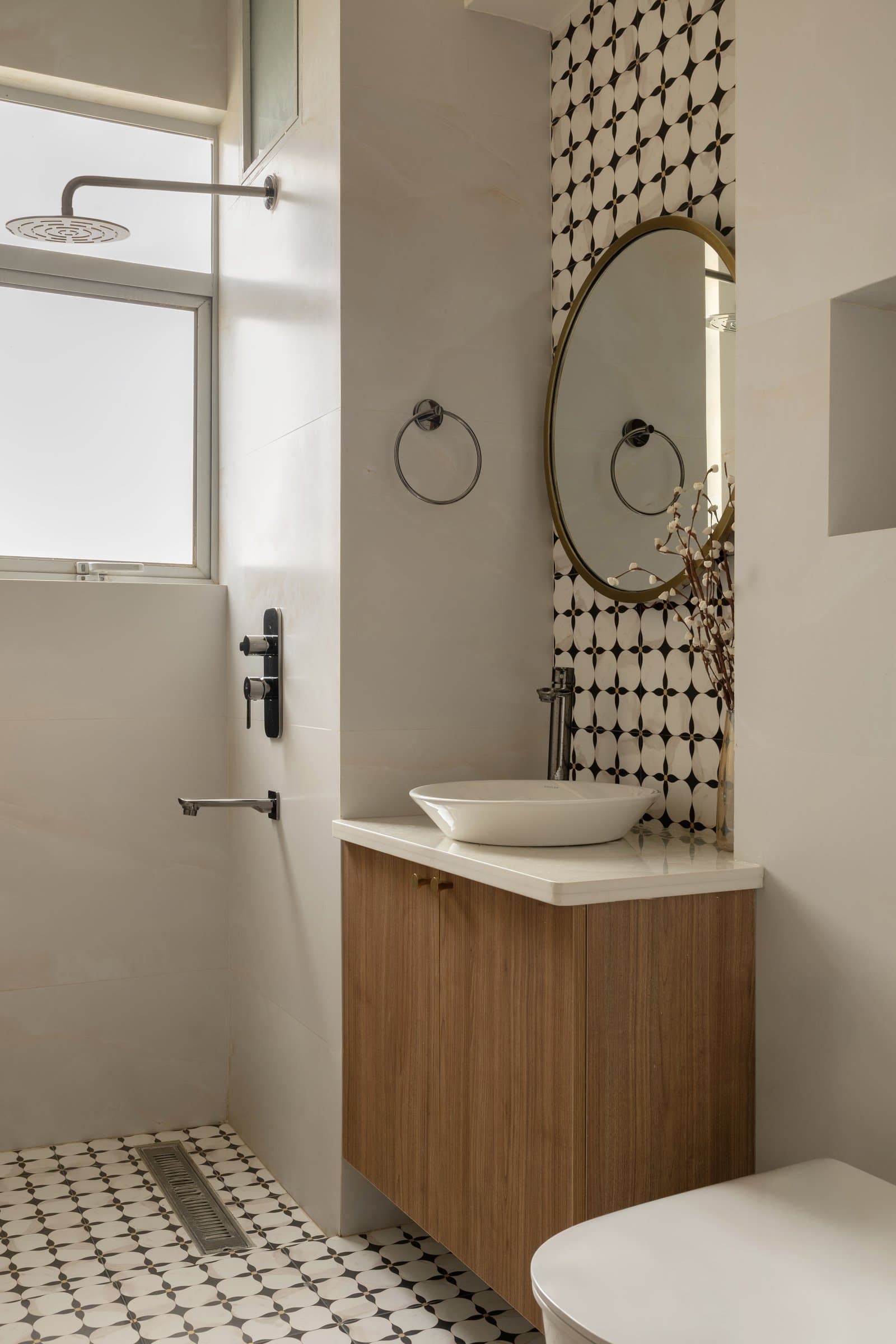 The second bathroom, where a full-height geometric floral tile column anchors a walnut vanity
