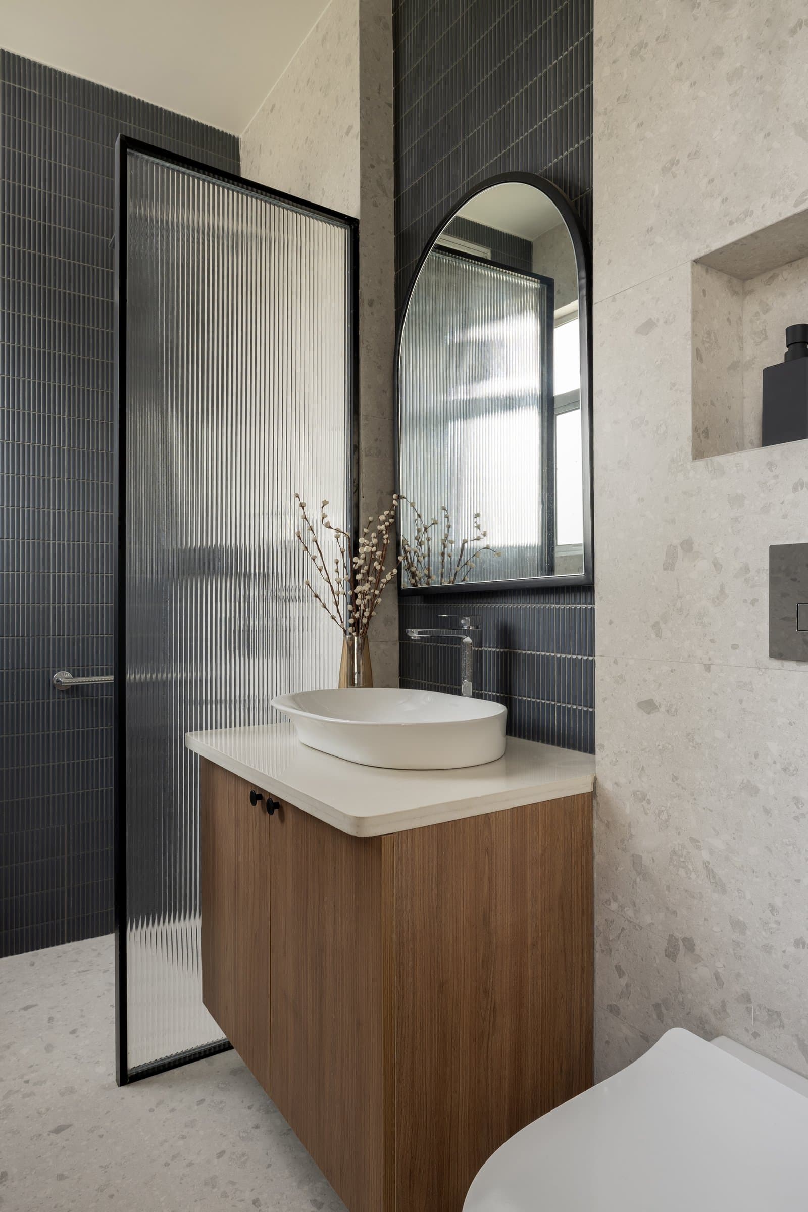 The master bathroom, where a vertical band of dark blue tile meets pale terrazzo-look walls
