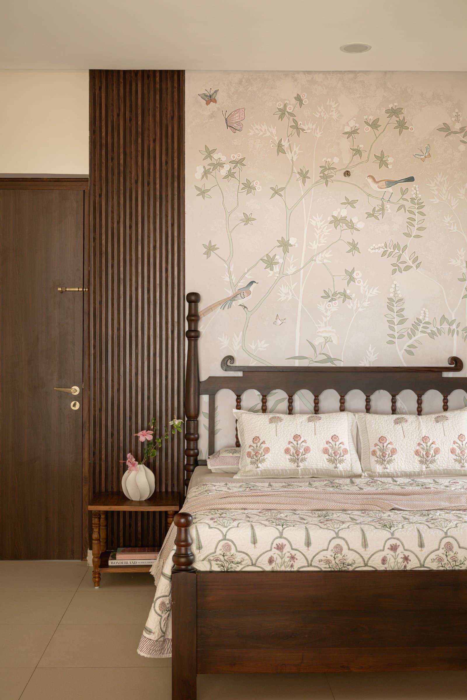 The primary bedroom, where a hand-painted mural of birds and blossoms holds the wall behind the four-poster bed