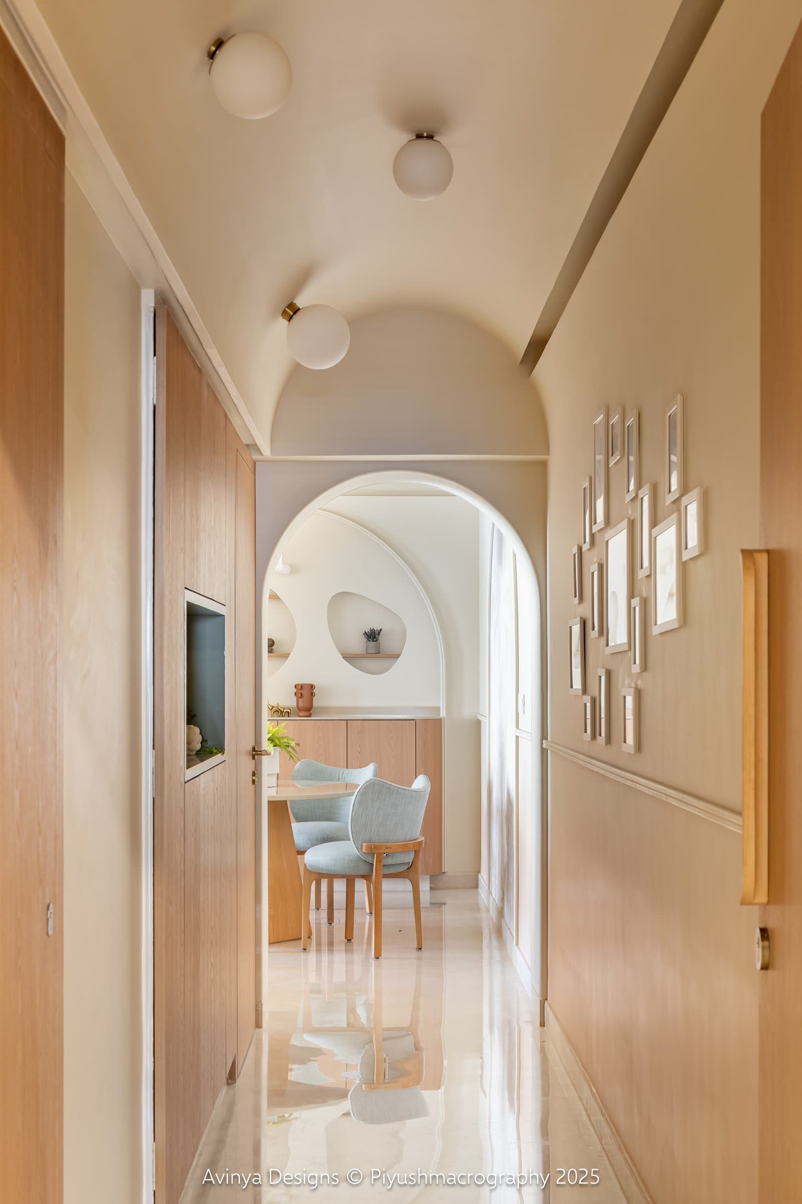 The passage, where a shallow vaulted ceiling with globe lights runs above a gallery wall of small framed photographs