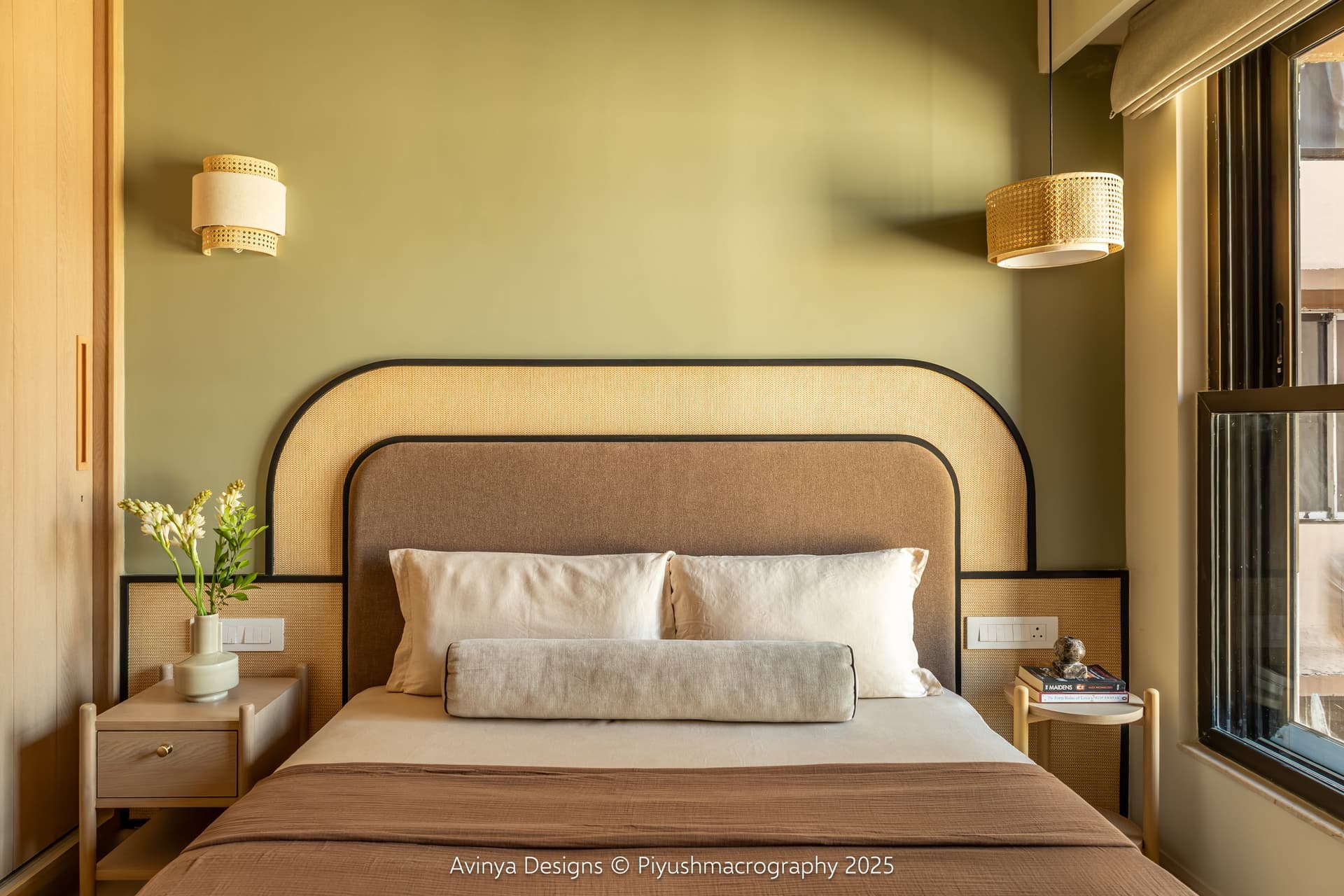 The second bedroom, where a sage wall backs a nested arched headboard of cane webbing and taupe upholstery