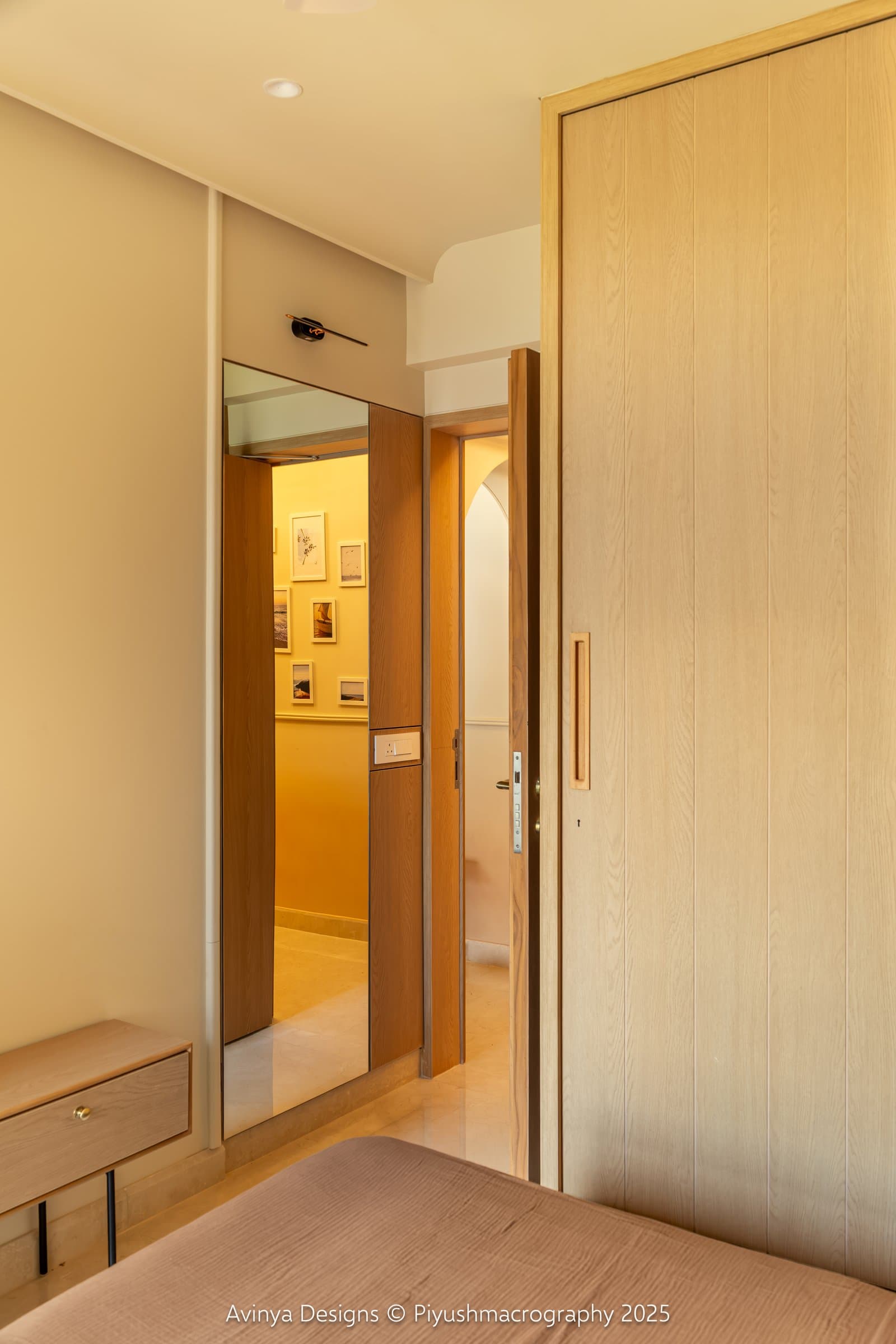 The bedroom threshold, where a full-height mirror beside an ash-toned door extends the material palette outward