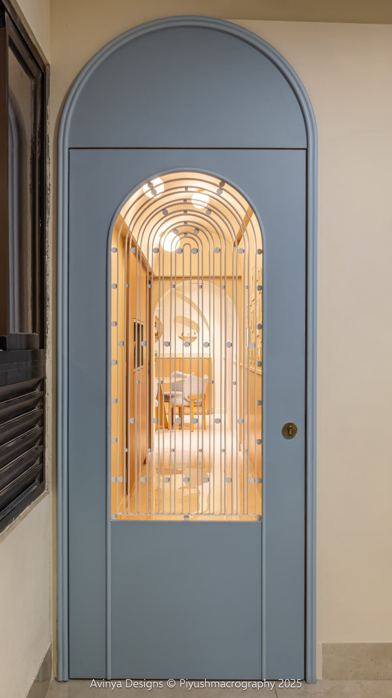 The entry, where a powder-blue arched door with a slim vertical grille offers a first framed glimpse of the interior