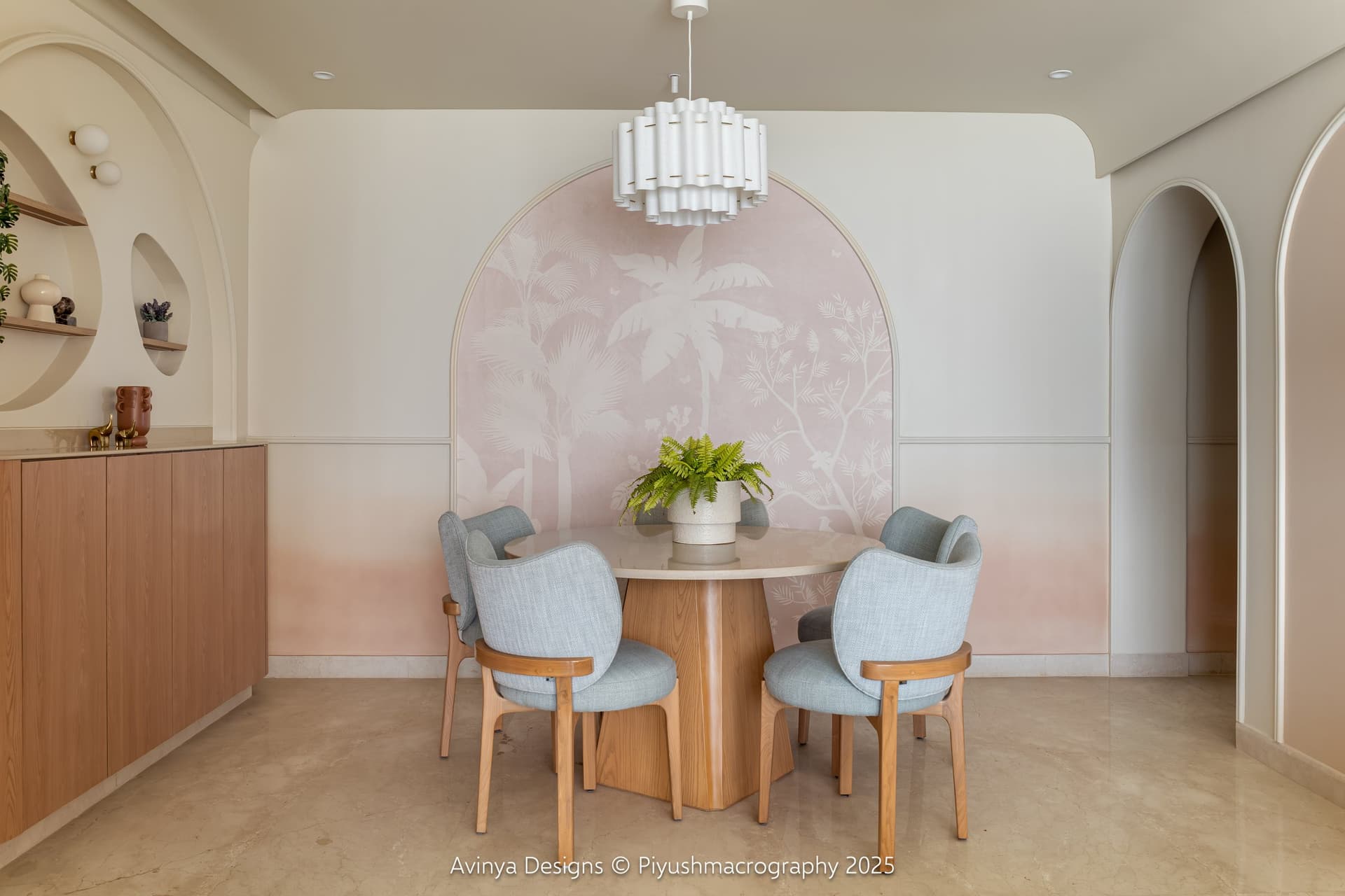 The dining area, where a hand painted tropical mural frames a round dining table beneath a fluted white pendant