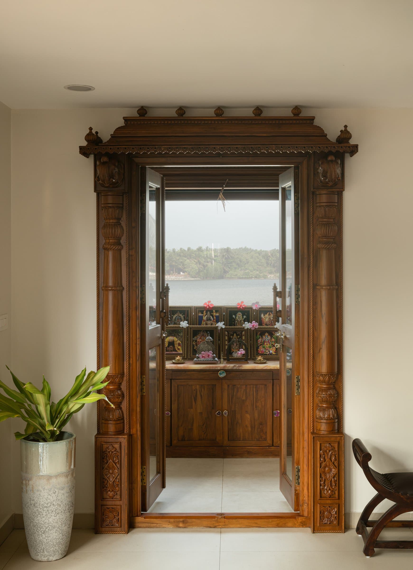 The pooja room, where a carved wooden doorway opens directly onto the river