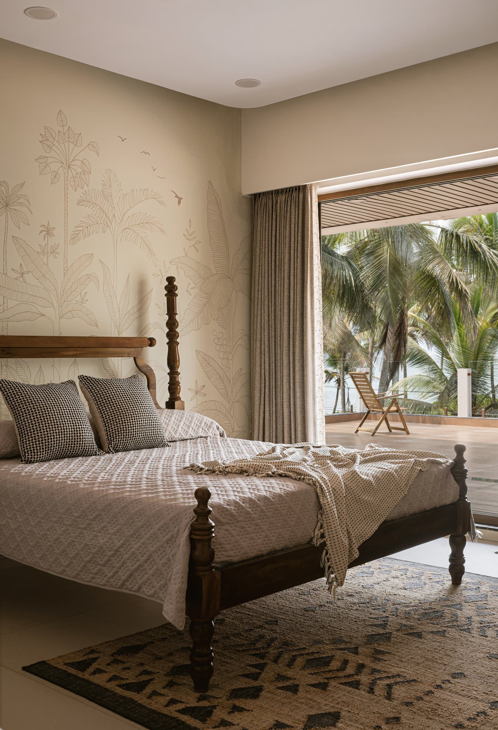 The sea-facing bedroom, where a line-drawn palm mural echoes the coconut grove beyond the sliding glass