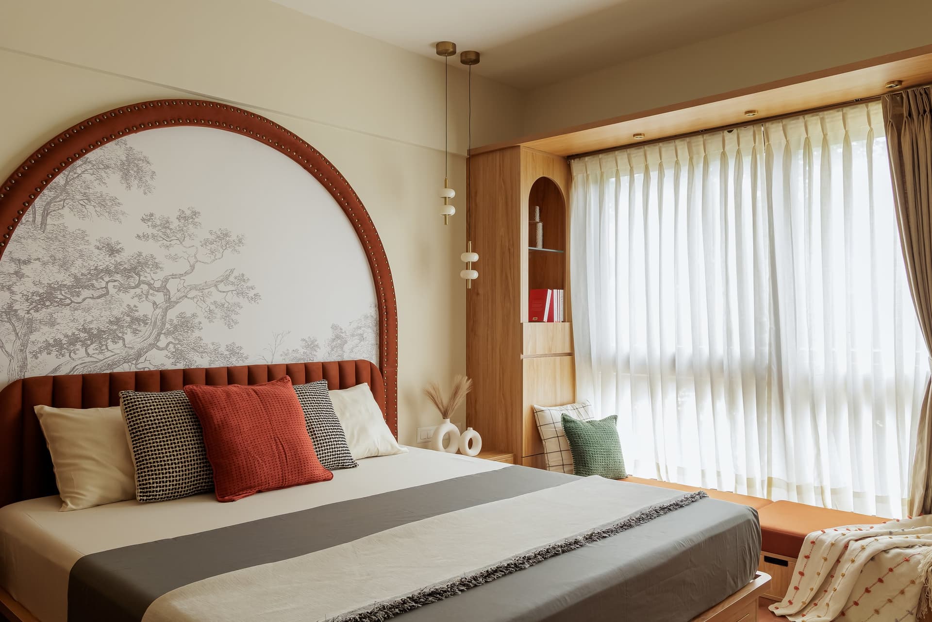 The master bedroom, anchored by a terracotta velvet channelled headboard set within a large arched feature wall