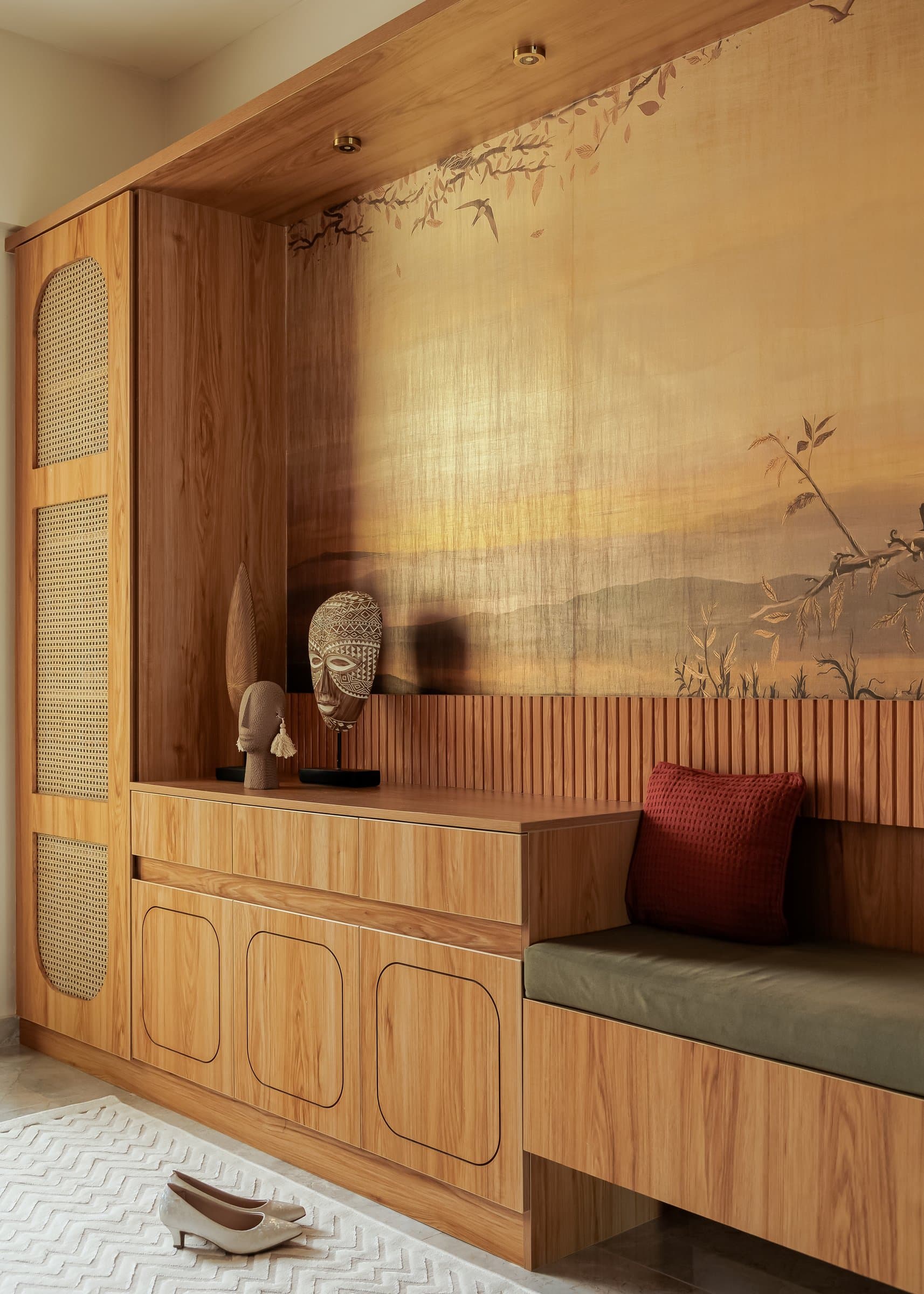 The foyer, where a metallic mural-inspired wallpaper and fluted wood joinery set the material register of the home