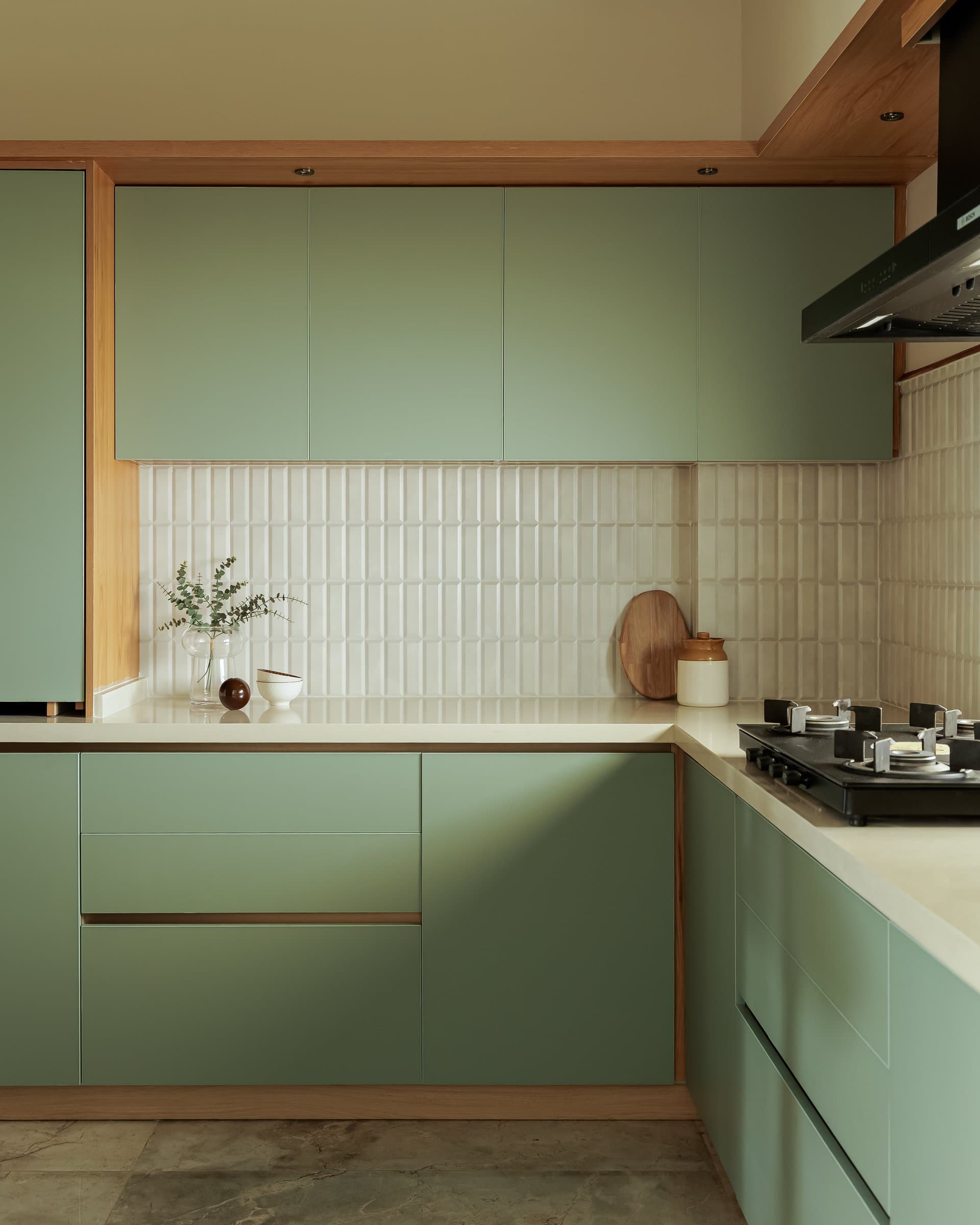 The kitchen, where muted sage cabinetry is paired with a dimensional pale tile backsplash