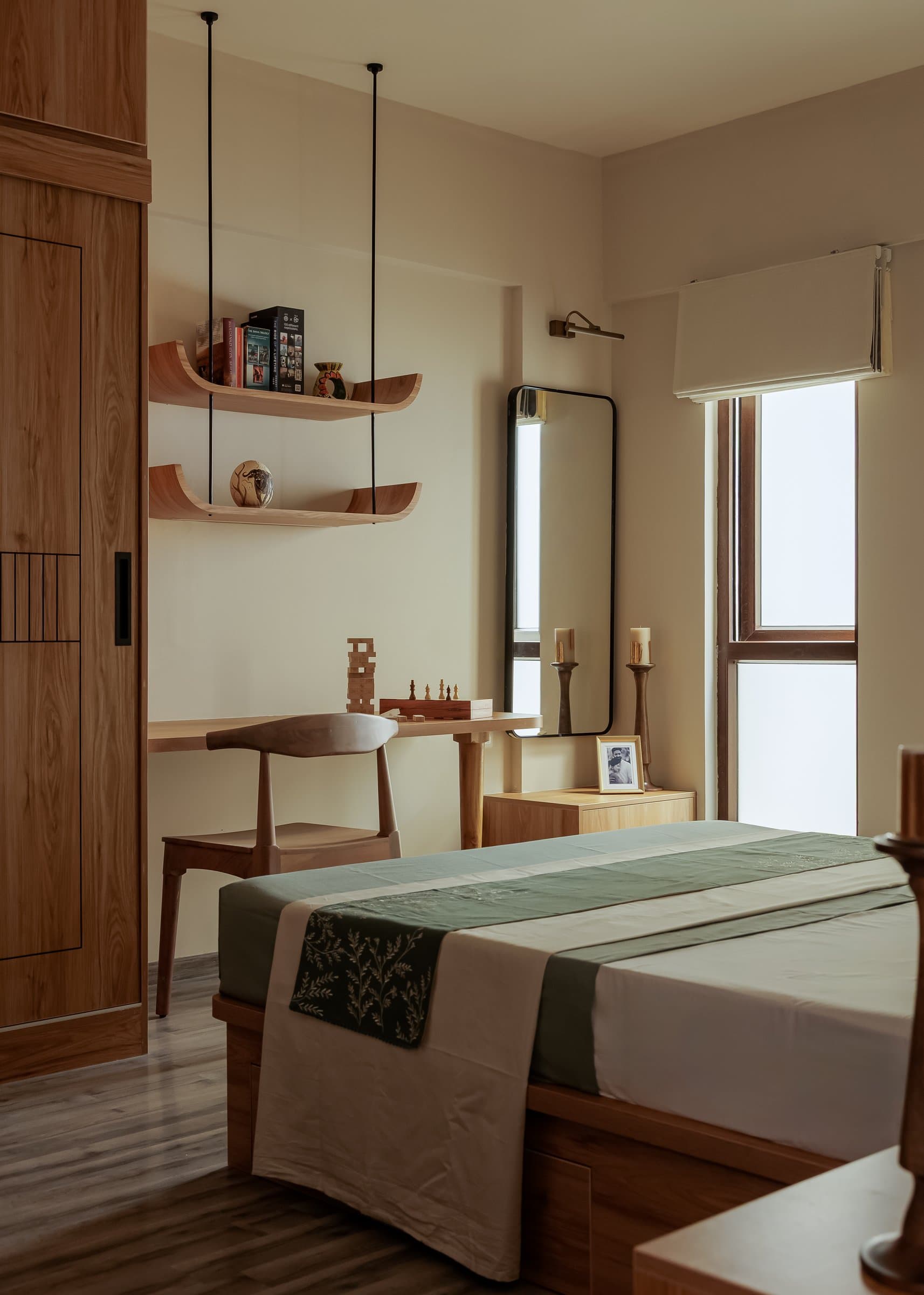 A wider view of the guest bedroom, where a compact writing corner with suspended wooden shelves extends the joinery along one wall