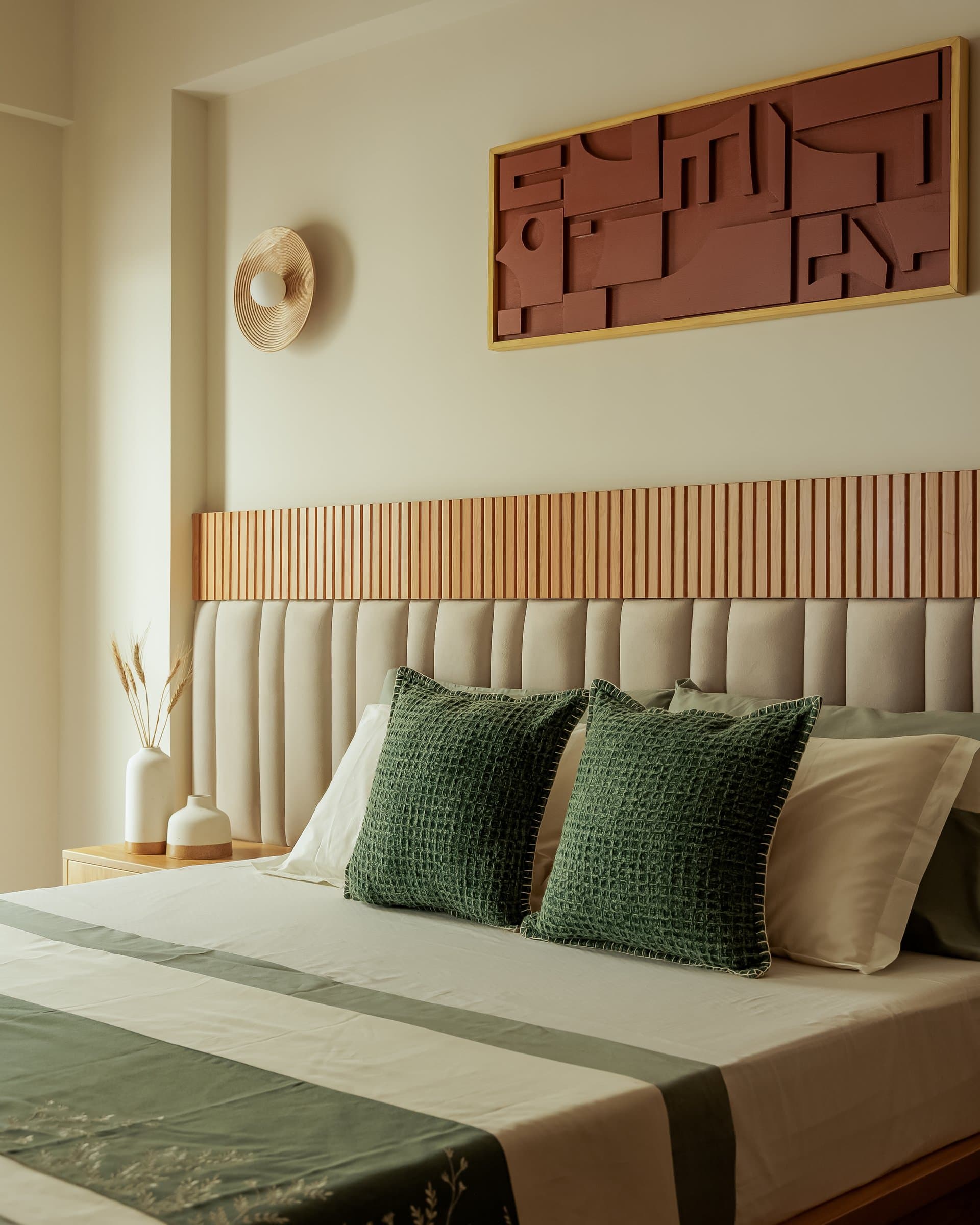 The guest bedroom, where a softly upholstered headboard is framed by a band of fluted wood