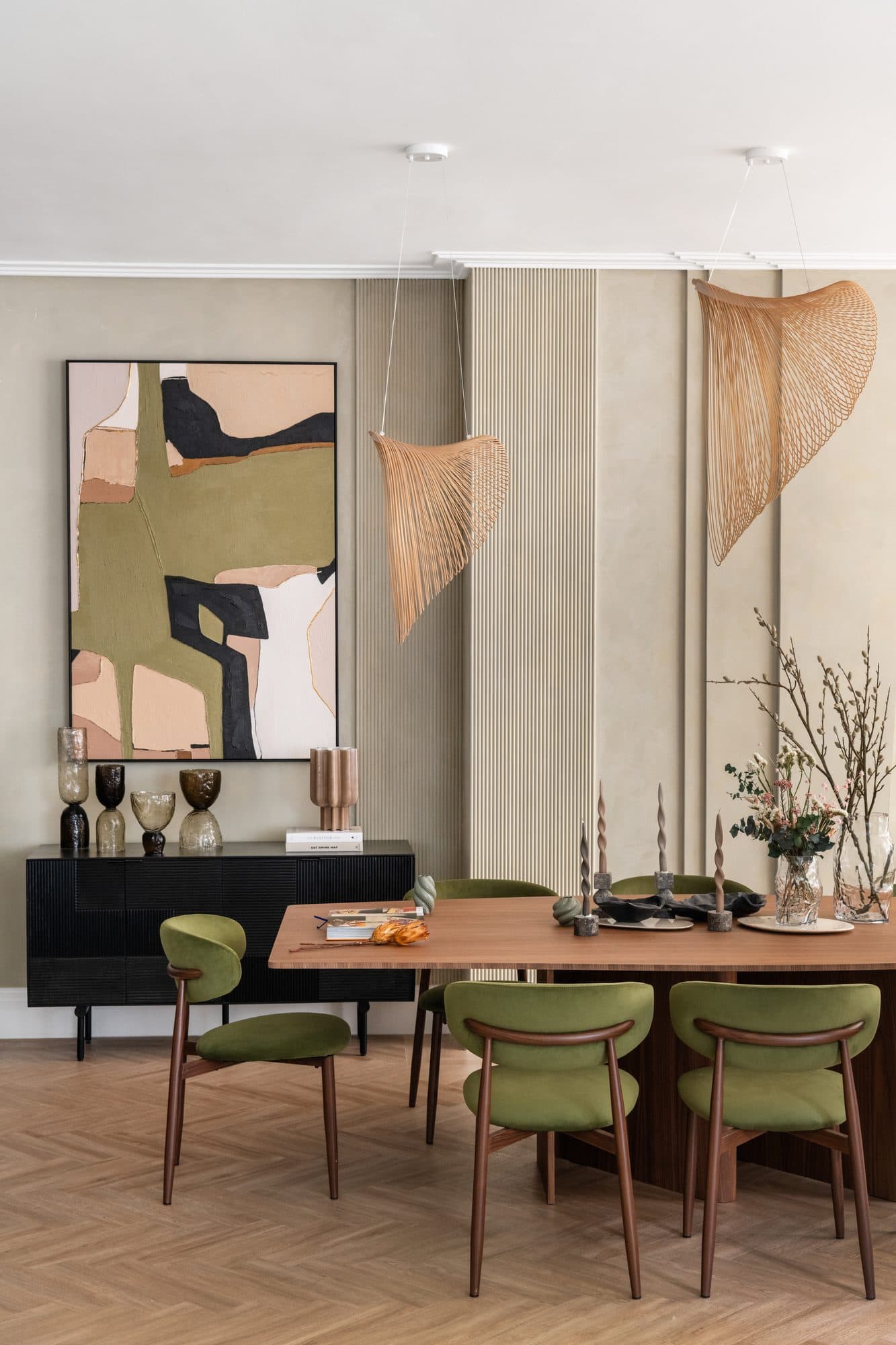 The Hampstead Home dining room — olive velvet chairs, herringbone parquet, woven pendant lights and an abstract earth-toned painting hold Wabi-Sabi restraint against English townhouse proportions.