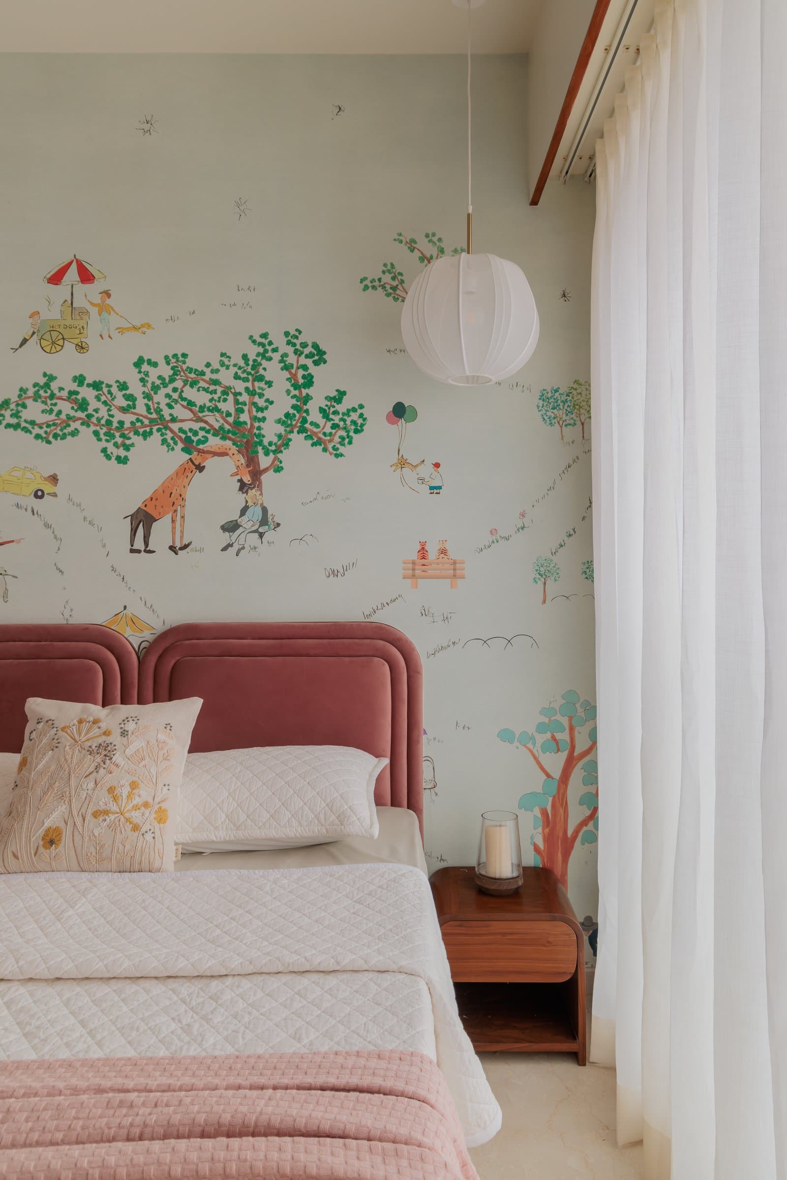 The child's room, where a hand-drawn park mural meets a stacked dusty rose velvet headboard