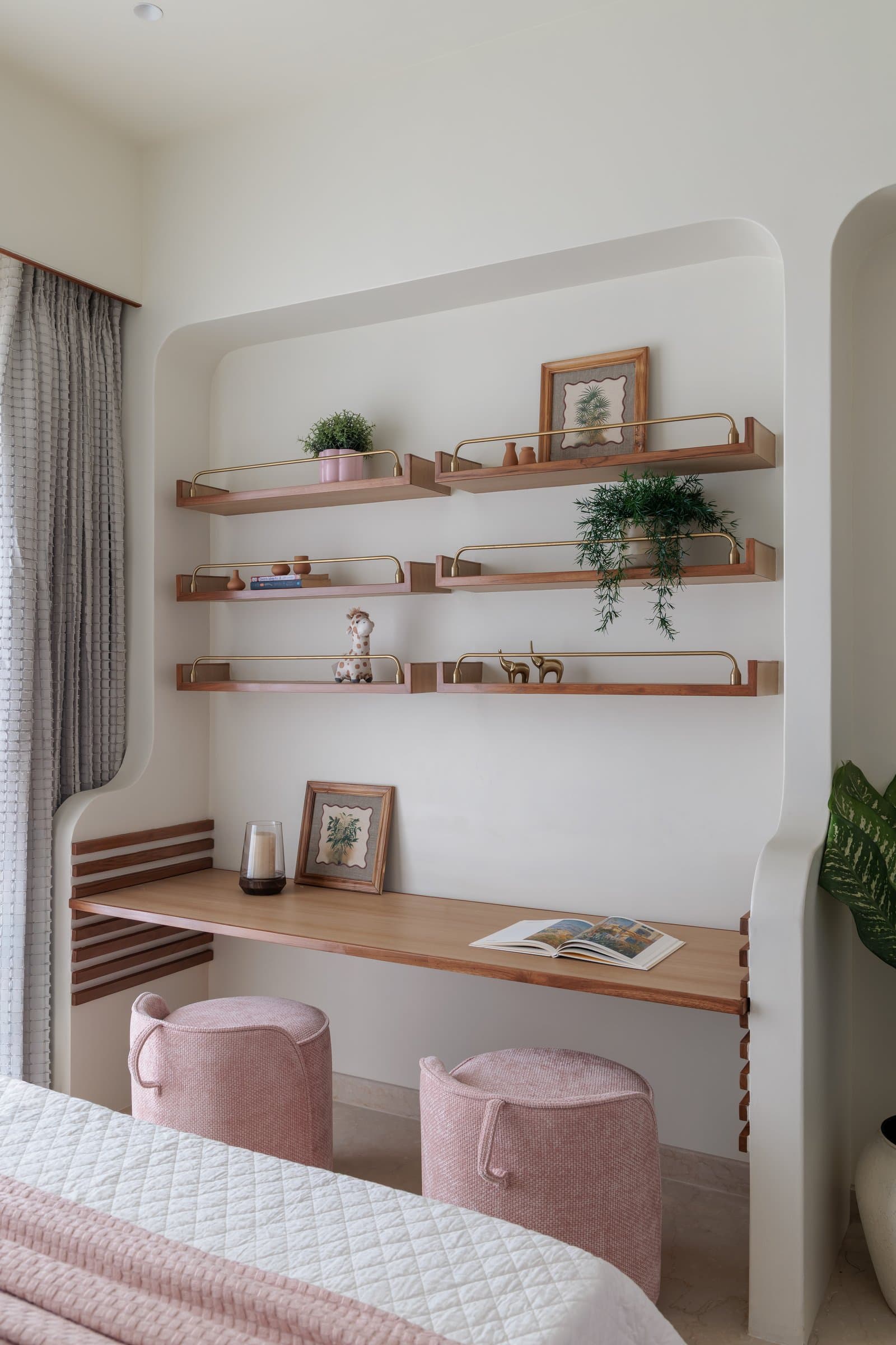 The curved study nook, where walnut shelves with slim brass rails frame a writing surface tucked into the bedroom