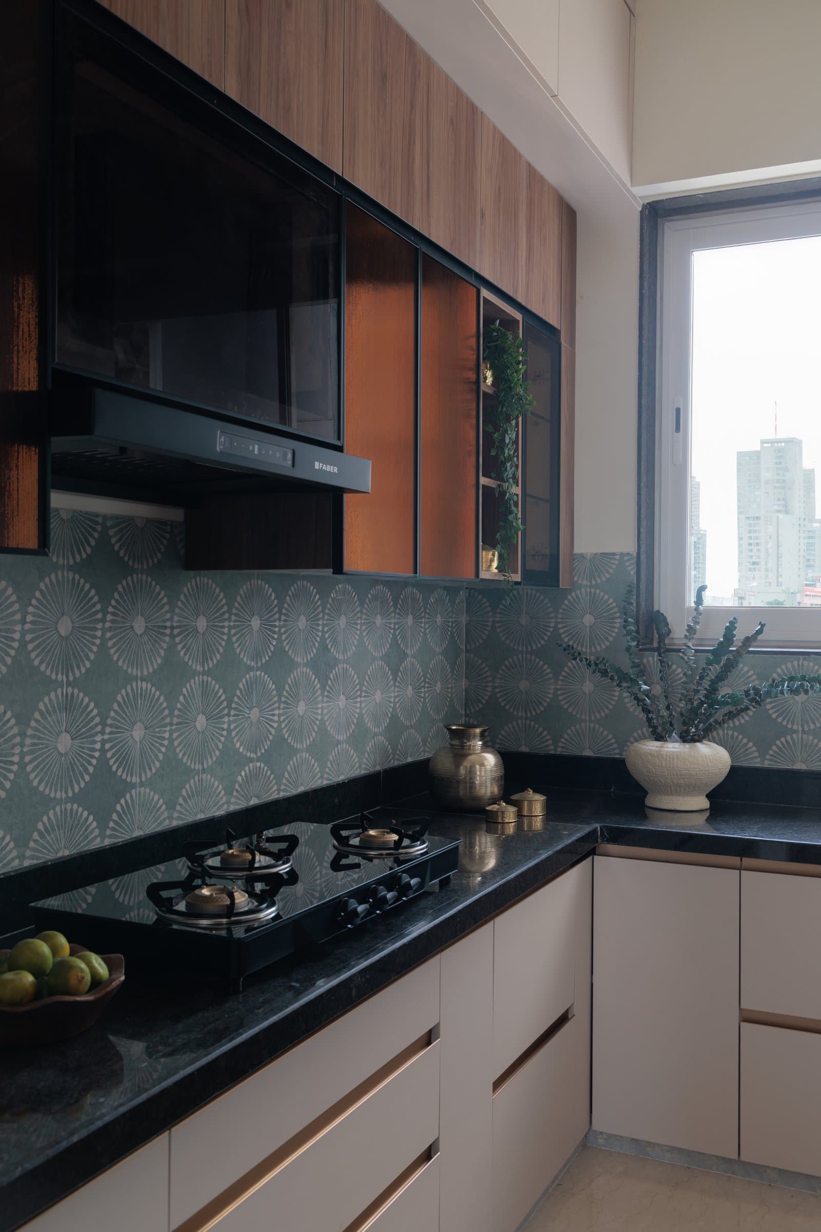 The kitchen, where a graphic patterned backsplash grounds warm timber uppers and off-white lowers