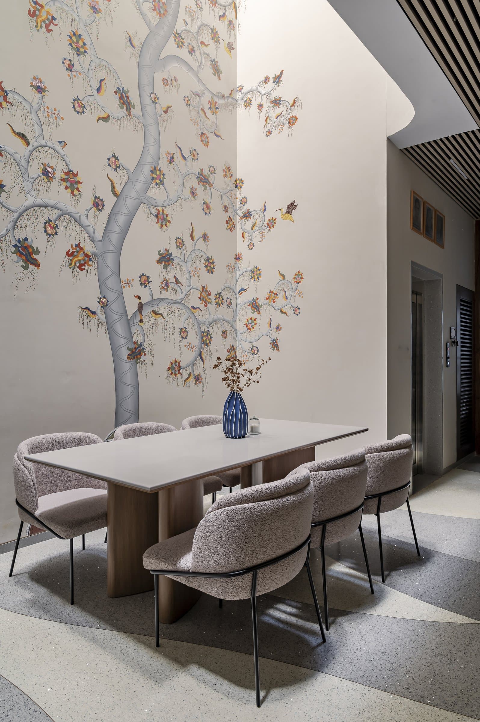 The dining wall, where the painted tree carries three storeys of vertical space