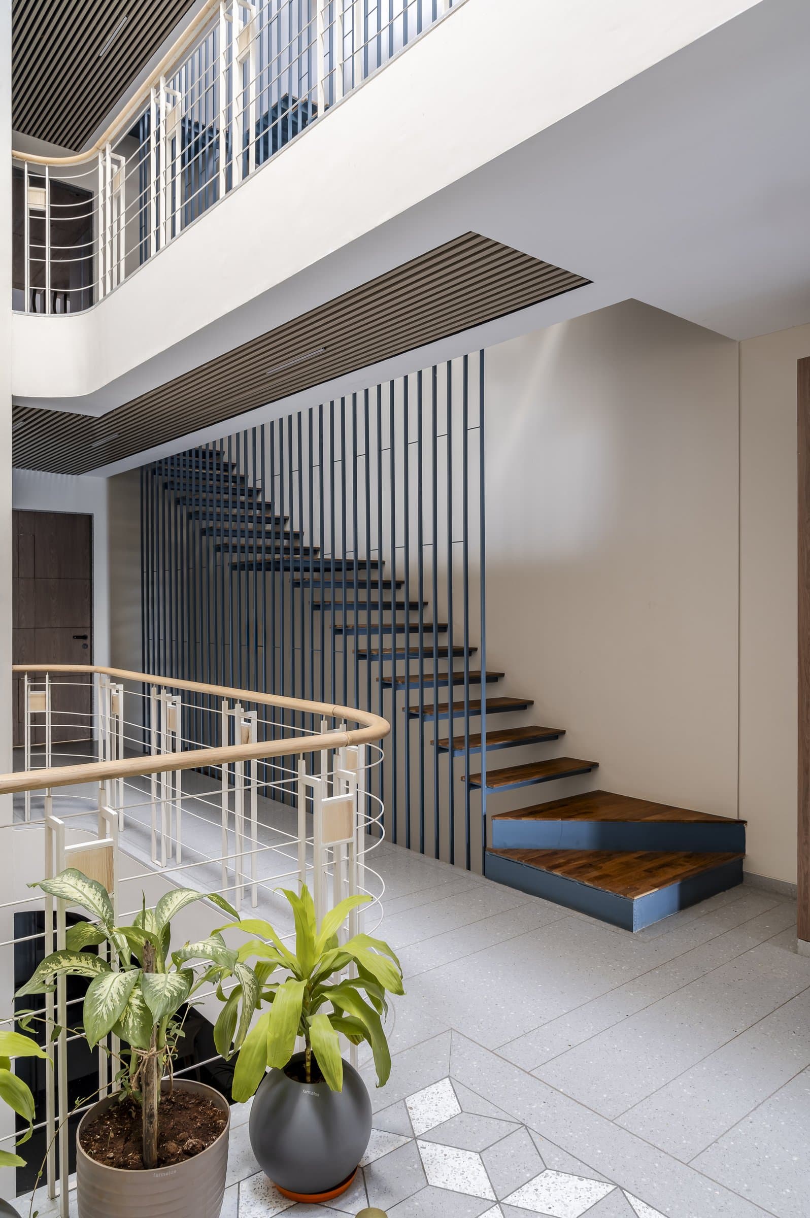 The fabricated blue metal staircase, its wood-topped treads floating alongside a slatted screen