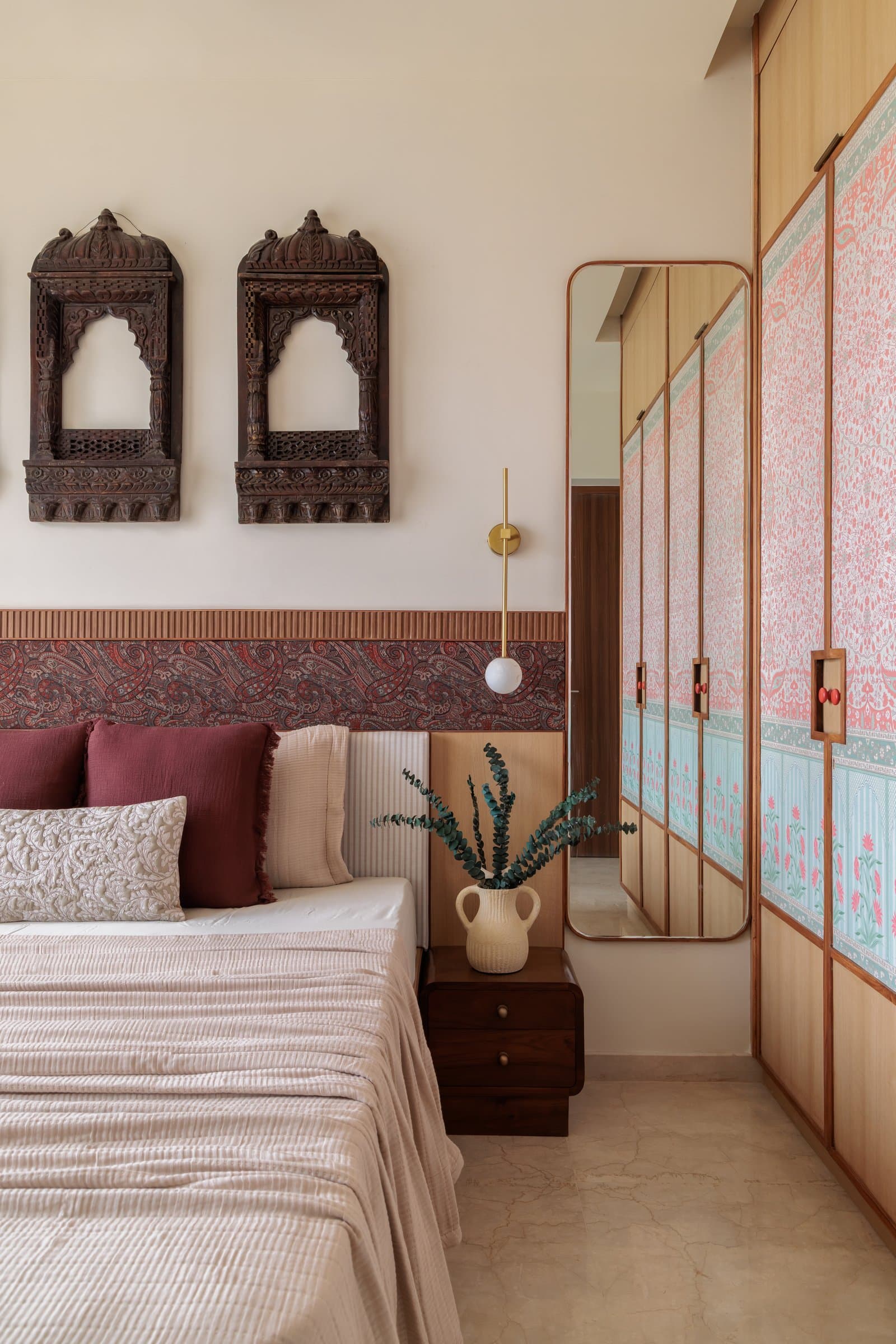 The master bedroom, where three antique jharokhas hang above a headboard wall of fluted timber and paisley