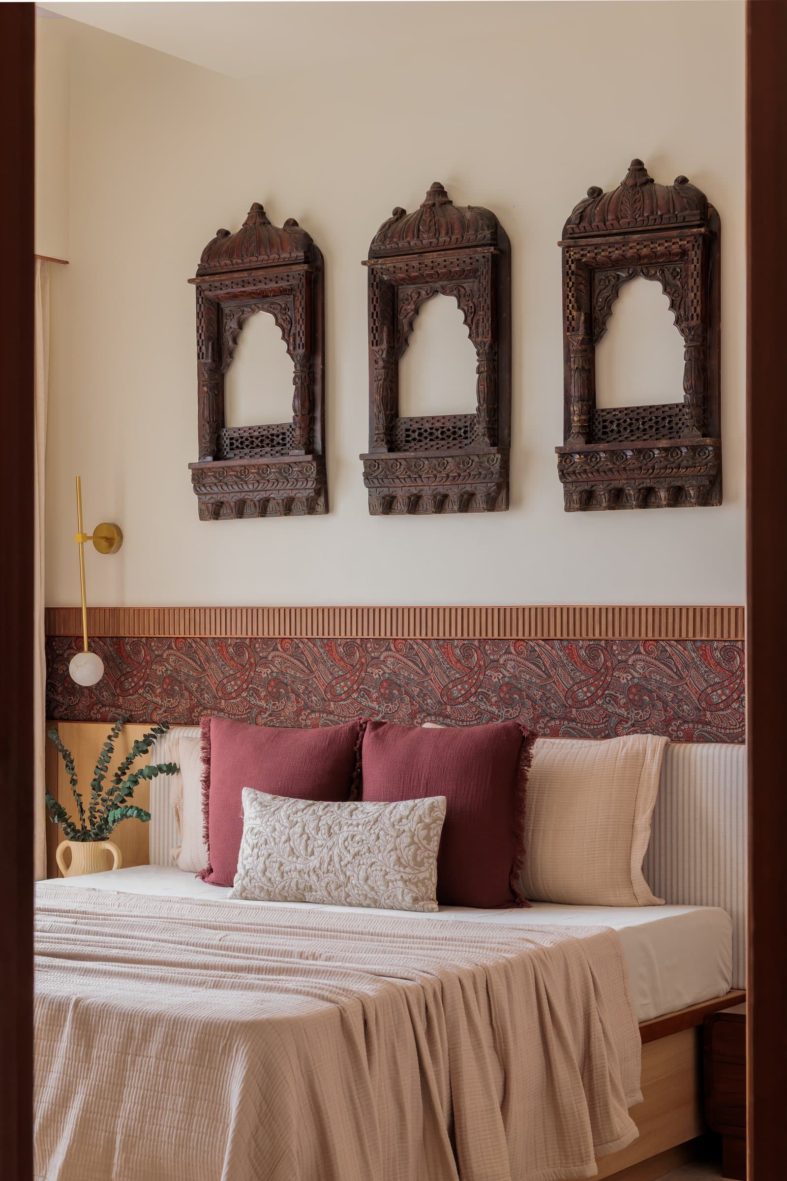 A closer view of the headboard wall, where jharokhas, paisley border, and striped upholstery settle into three horizontal registers