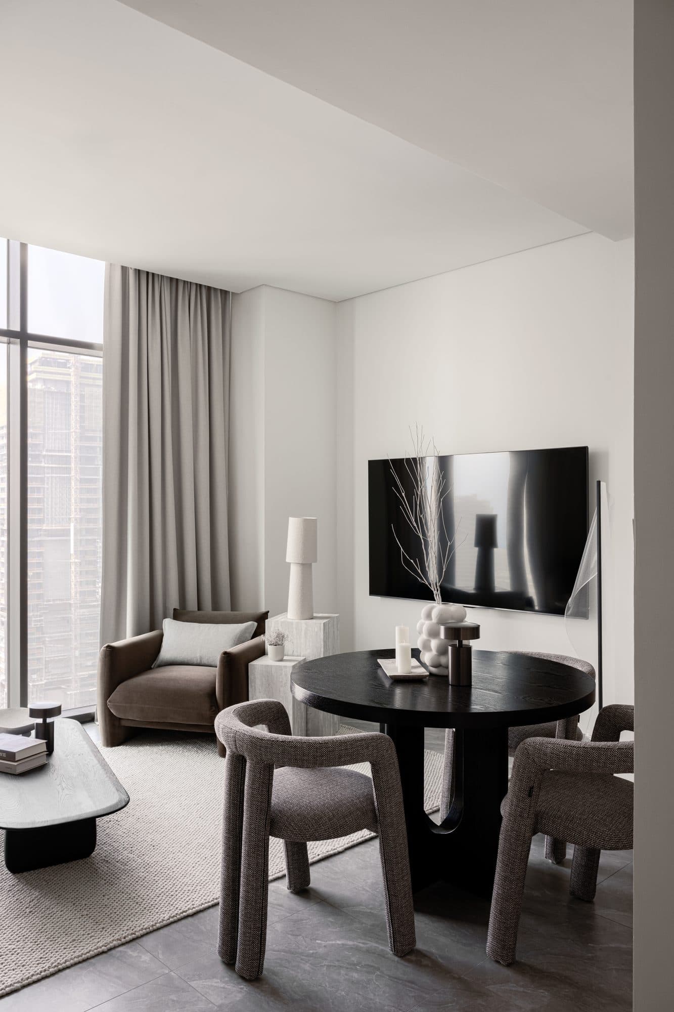 The Peninsula One living room, with the Dubai skyline framed through floor-to-ceiling curtains — round forms, warm textures, and the view as the interior's originating idea.