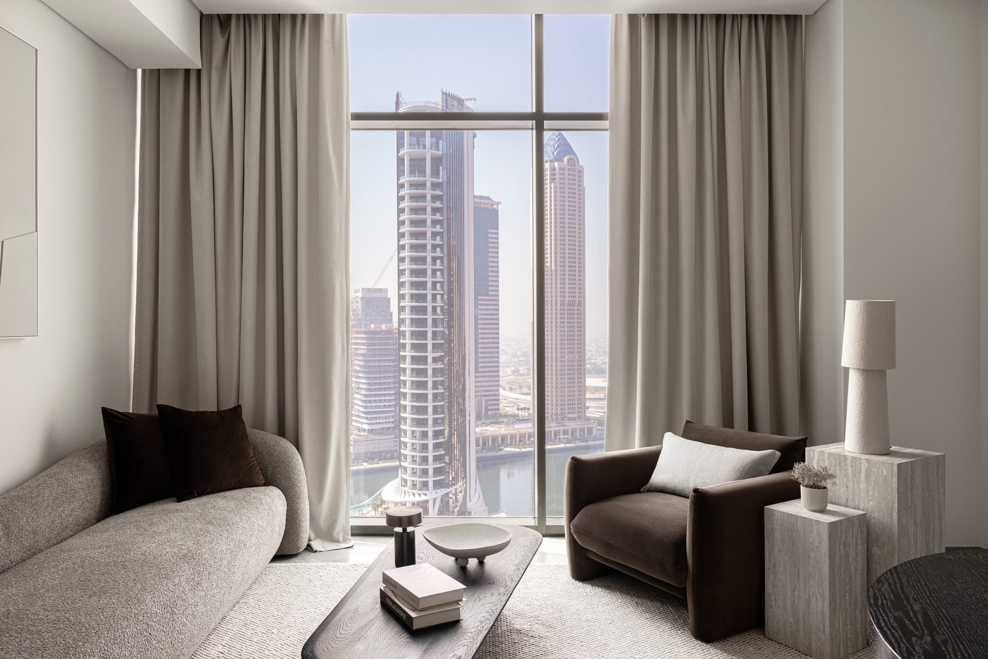 The reason for the palette: a floor-to-ceiling window onto the Business Bay canal, framing the towers the studio built the interior to converse with.