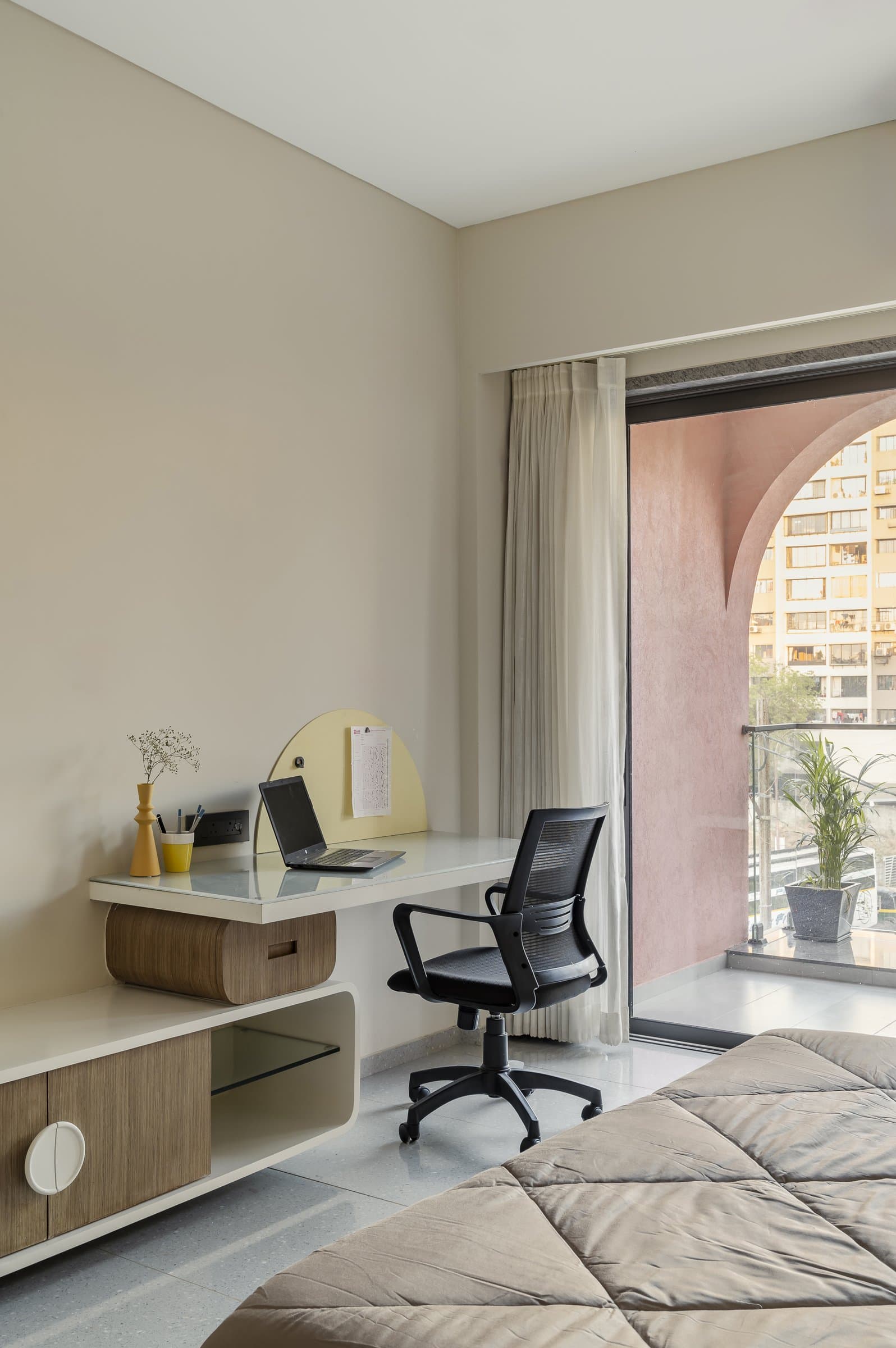 The study nook, where a wall-hung desk faces the arched terracotta balcony beyond