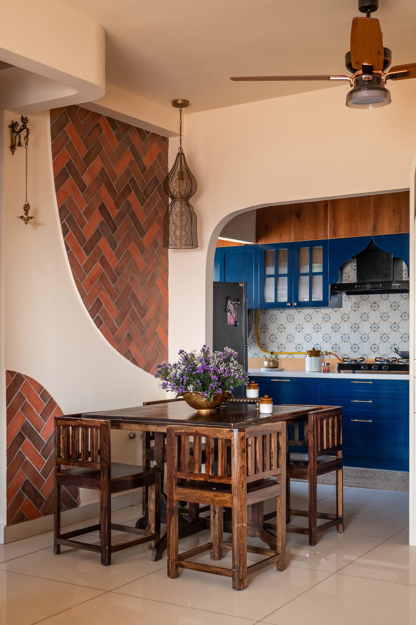 The dining area, where a sweeping arc of herringbone-laid terracotta tiles anchors the transition between living room and kitchen