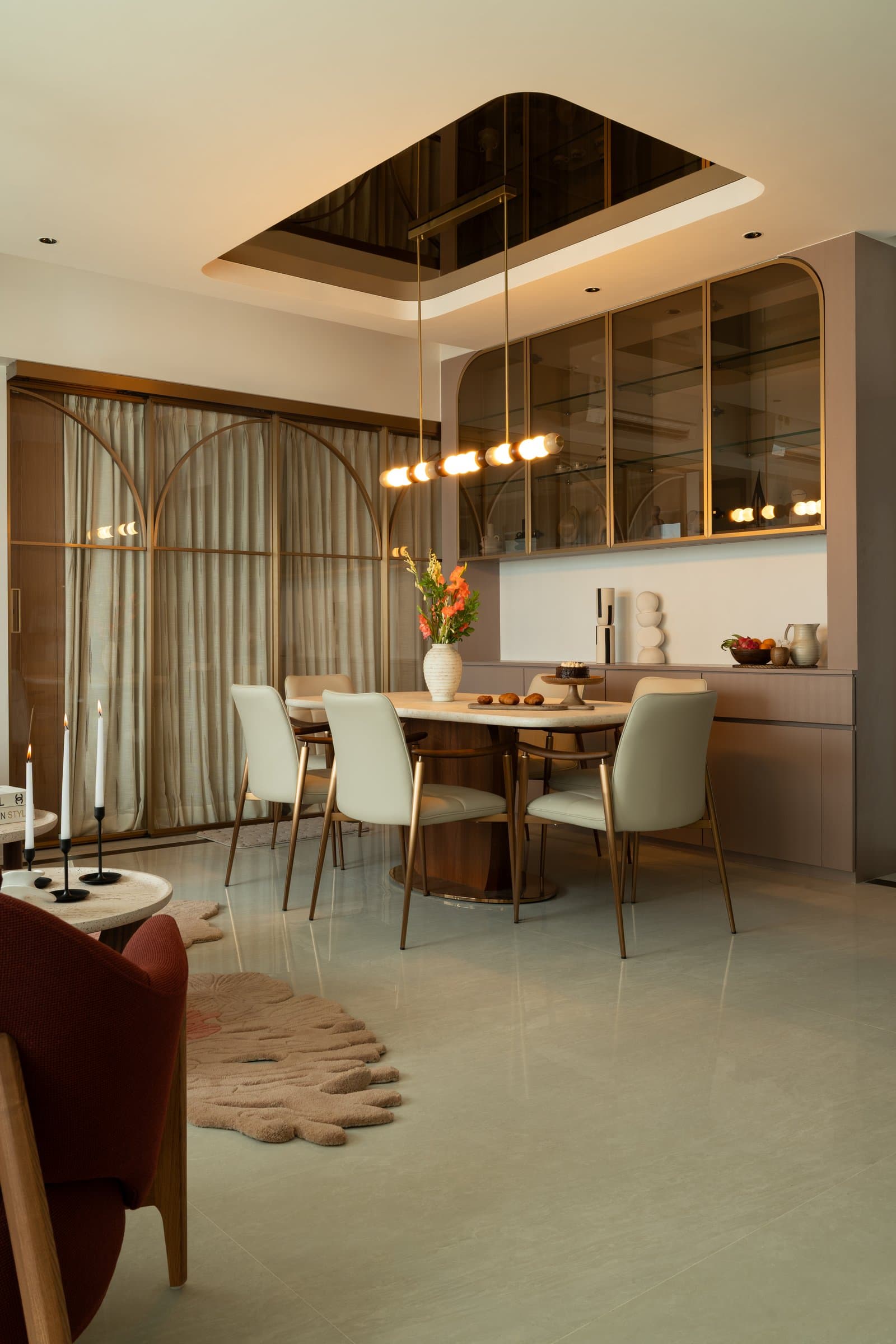 The dining area, with its walnut oval table, bronze pedestal base, and recessed bronze mirror inset in the ceiling