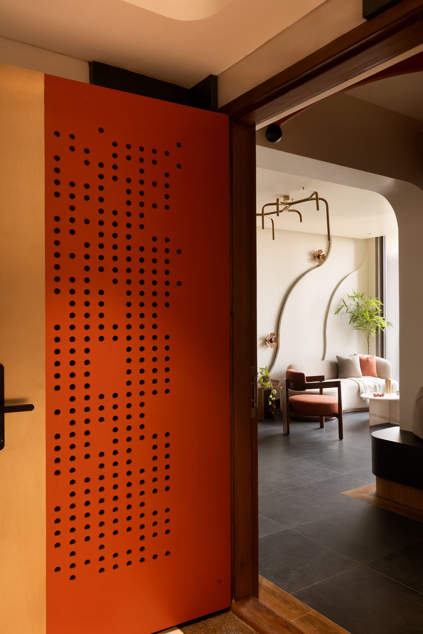The entry threshold, where a perforated terracotta door frames a first glimpse of the living room beyond