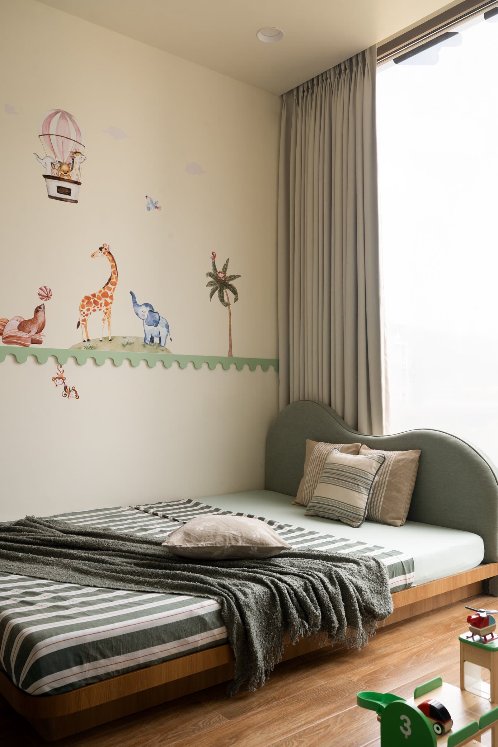 The children's bedroom, where a playful mural rises above a scalloped sage-green trim
