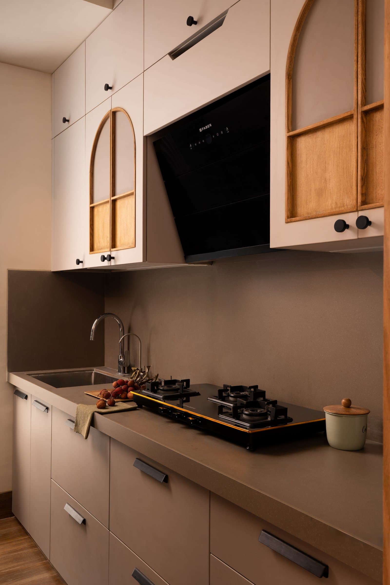The kitchen, where arched glazed upper cabinets echo the dining niche in a softer tonal register