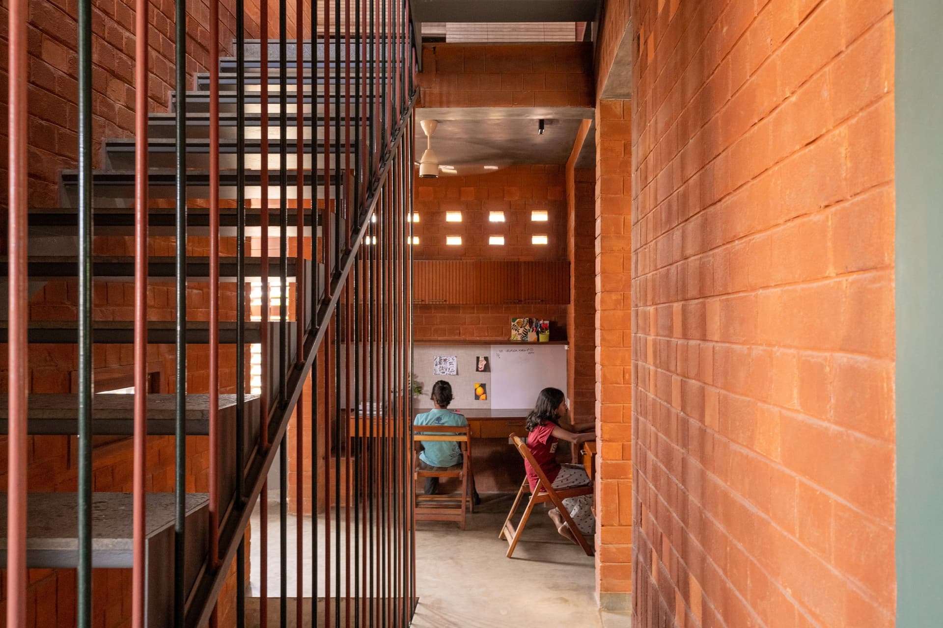 A children's study nook lit by square perforations in the brick wall
