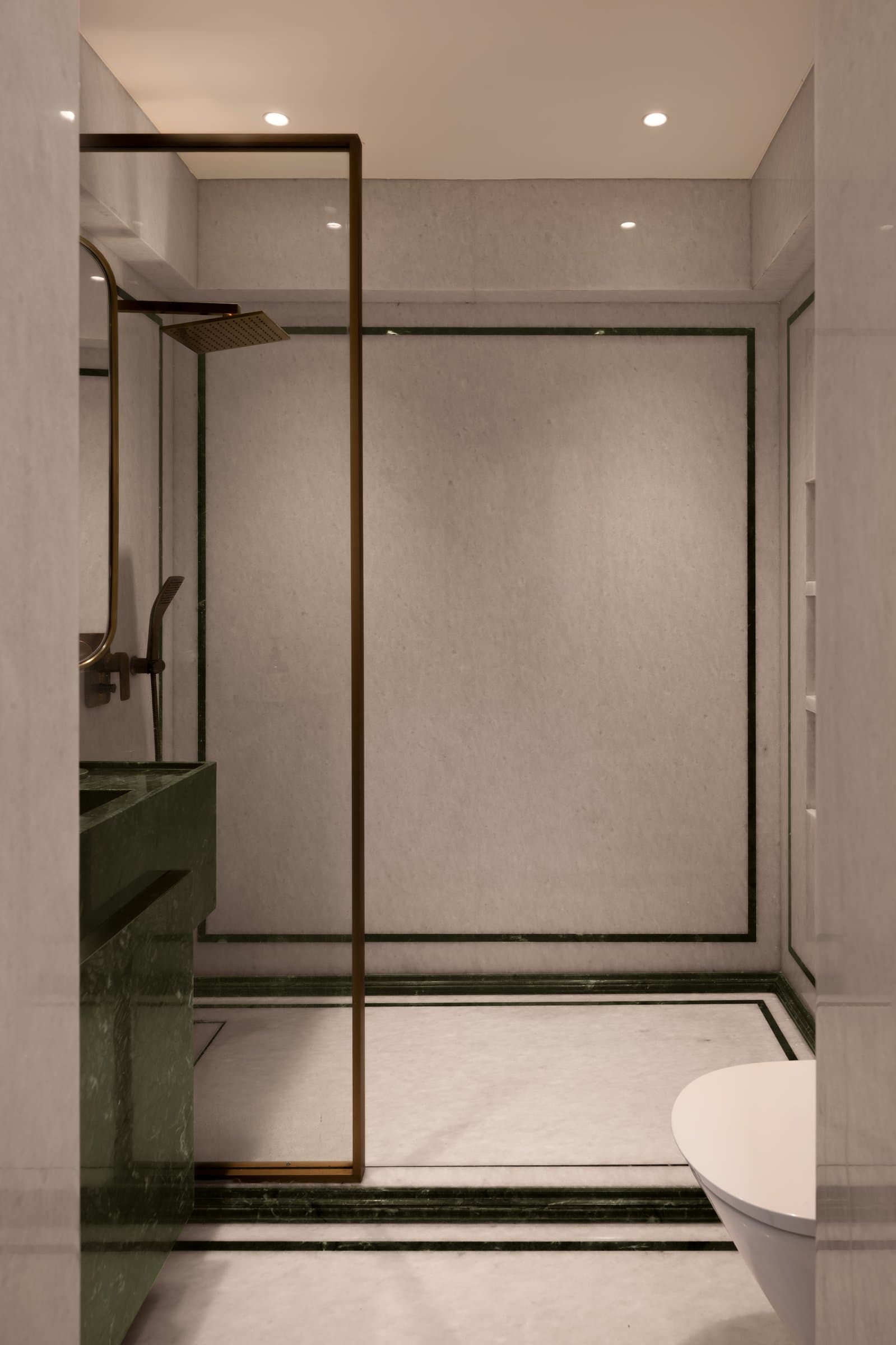 The master bathroom, where cream stone and green stone banding create a quiet architectural drawing on the walls