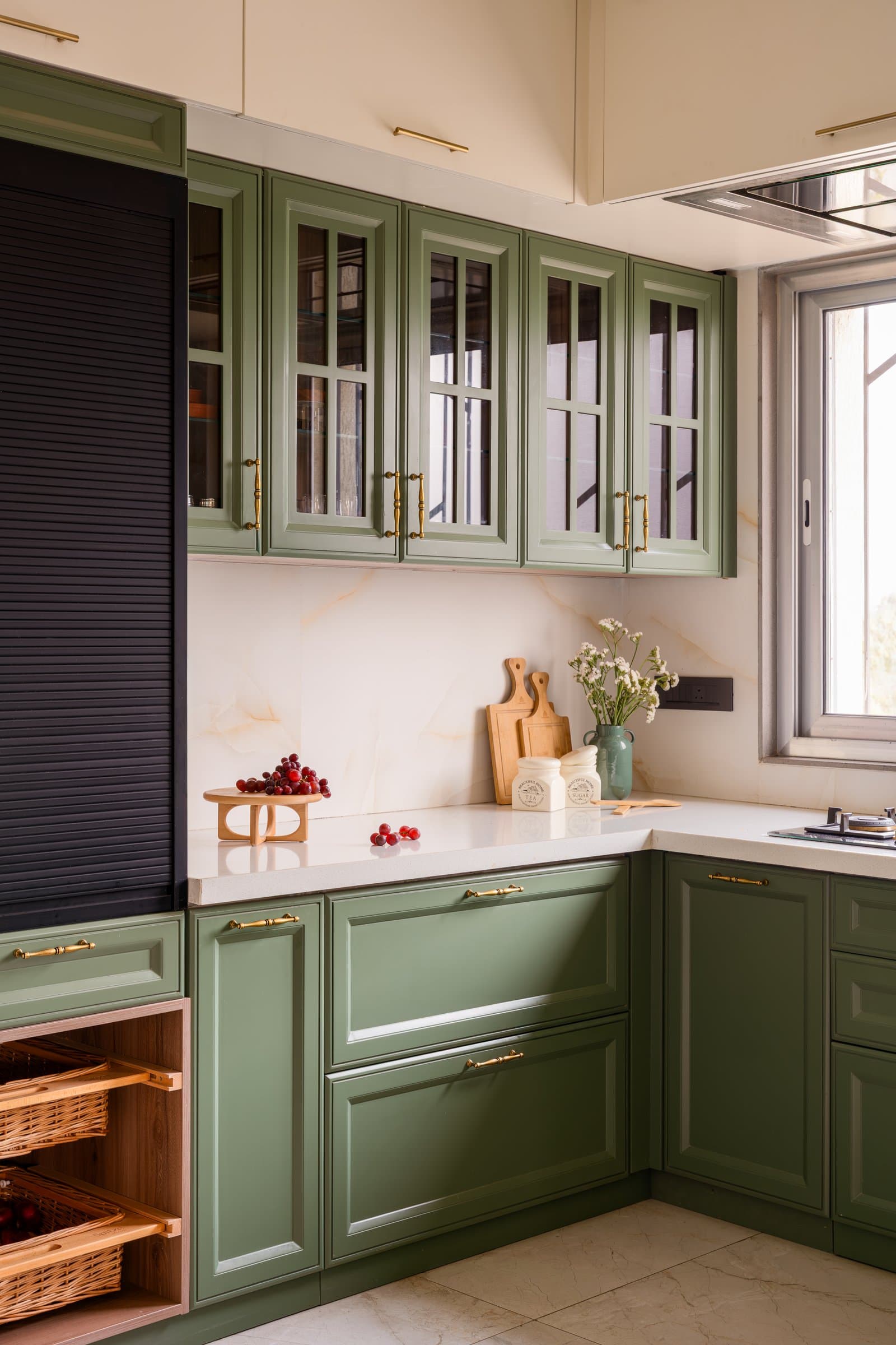 The kitchen, where sage cabinetry with brass pulls meets a veined stone backsplash