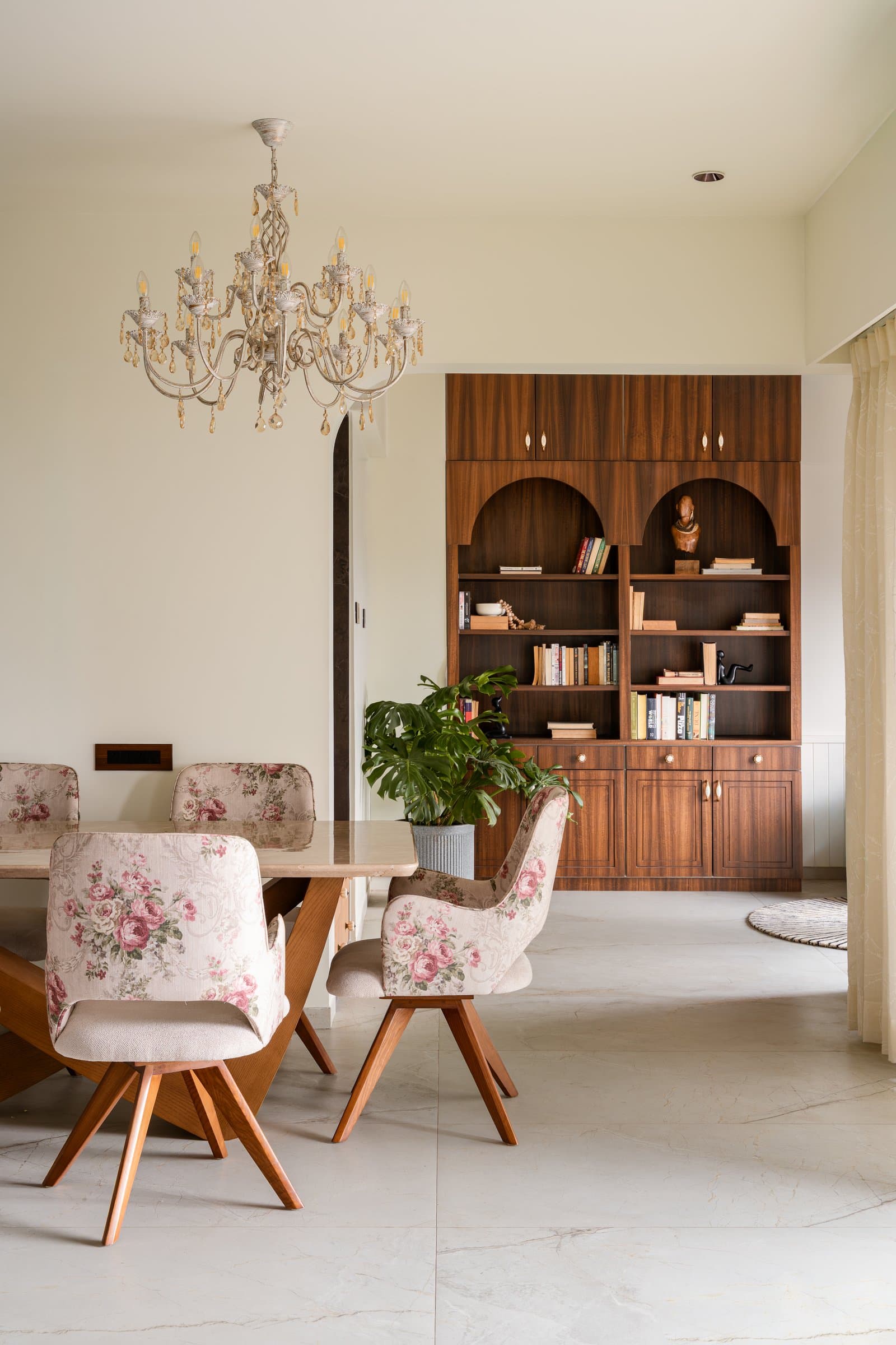 The dining area, where the library wall becomes a visible backdrop and a crystal chandelier anchors the room