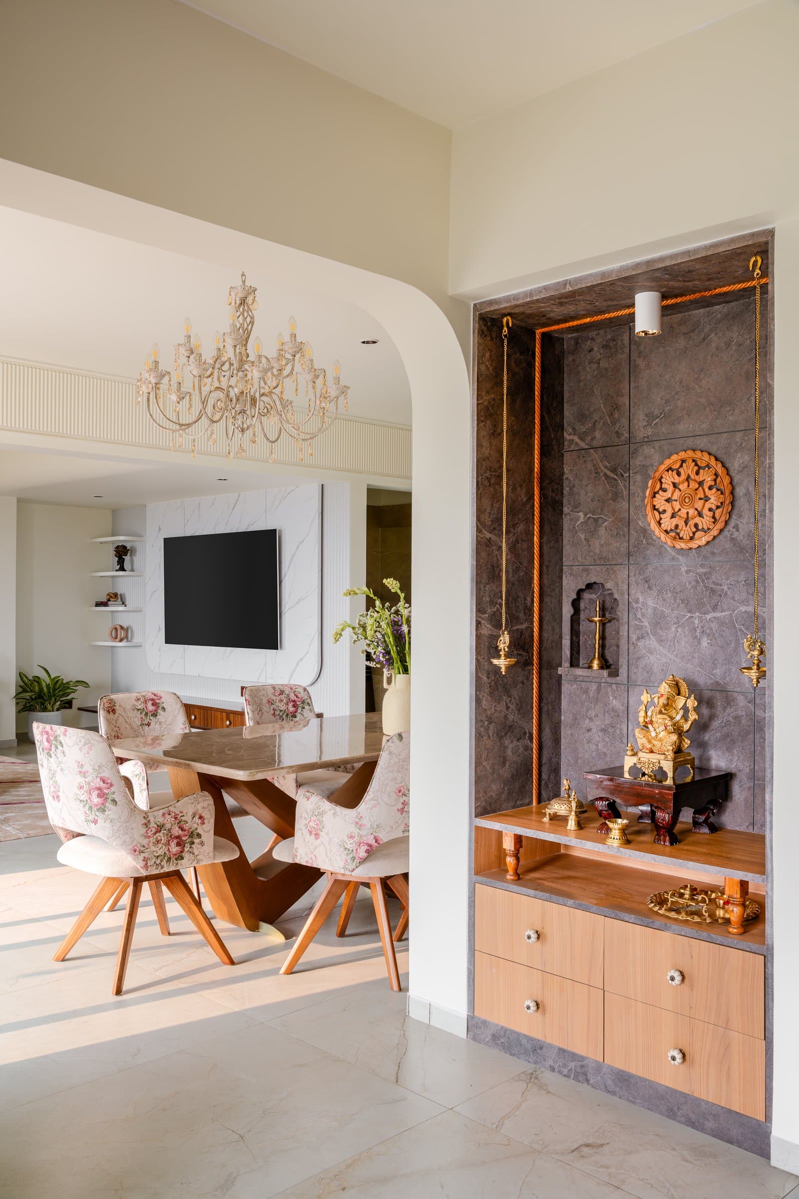 The pooja niche, where a dark stone surround and a warm wood cabinet frame the household's daily ritual