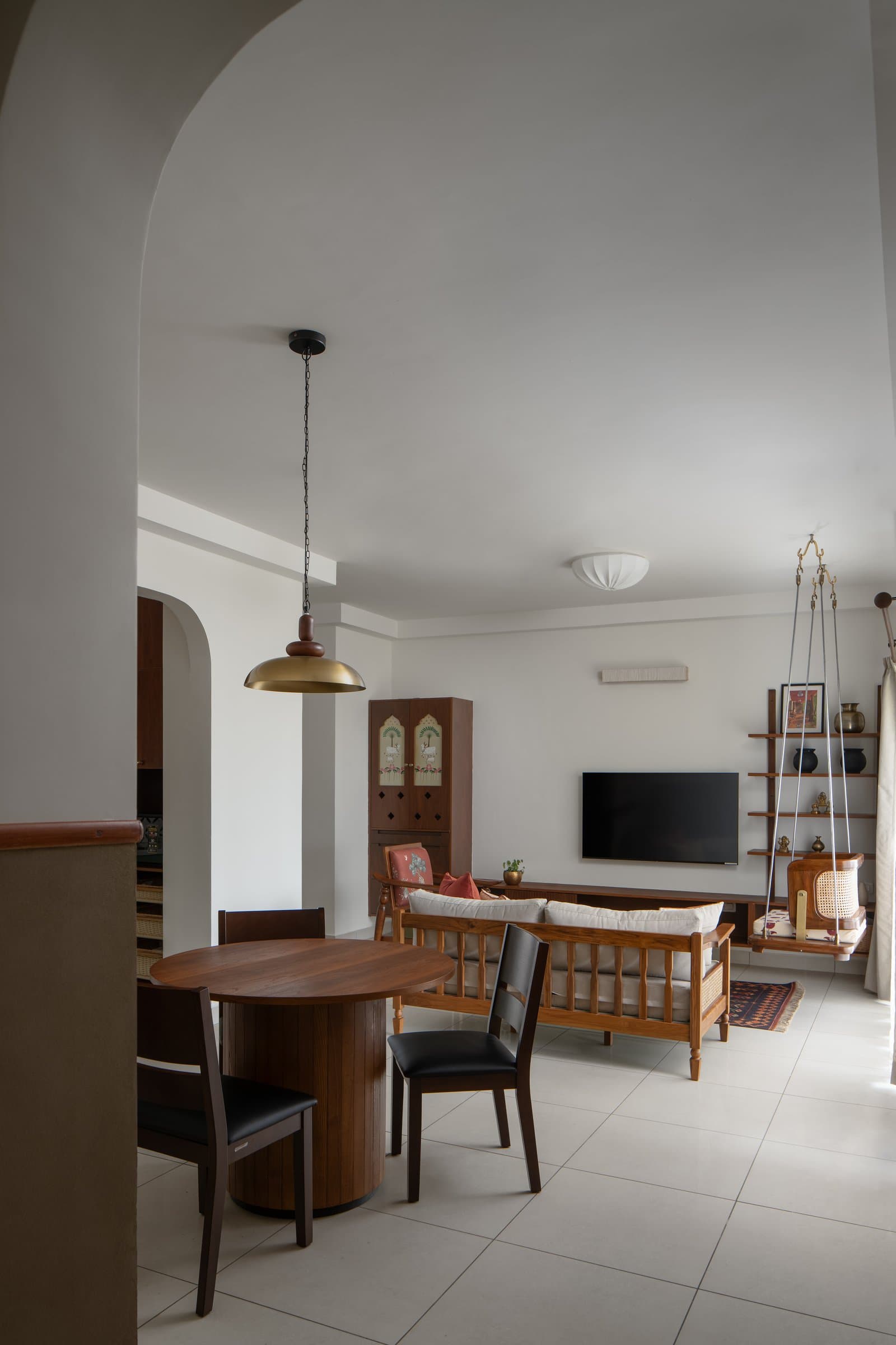 The living and dining spaces flow together beneath a soft arched opening in the plaster ceiling