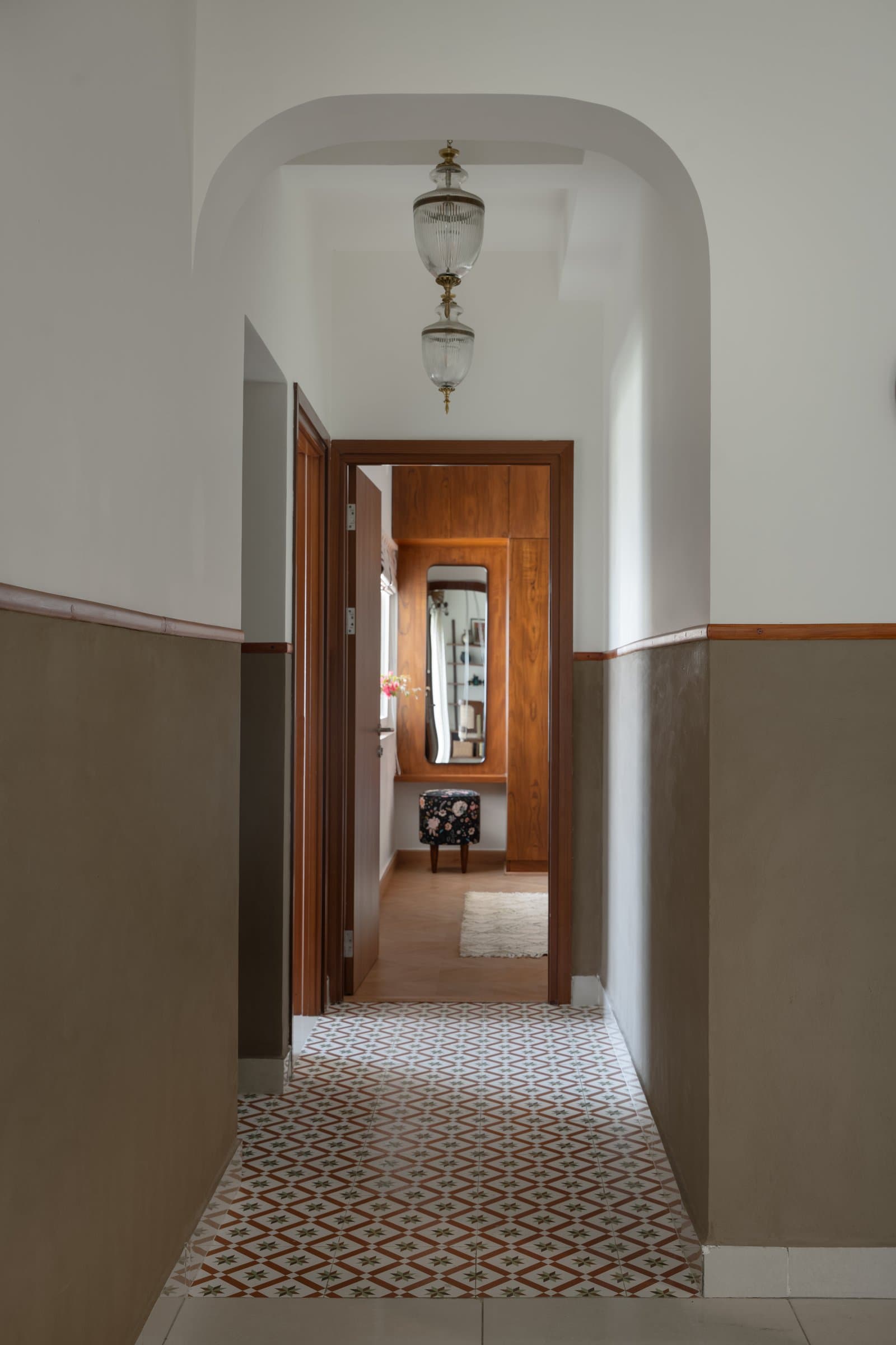 The passage to the bedrooms, lined with encaustic-style tiles and lit by glass-and-brass pendant lanterns