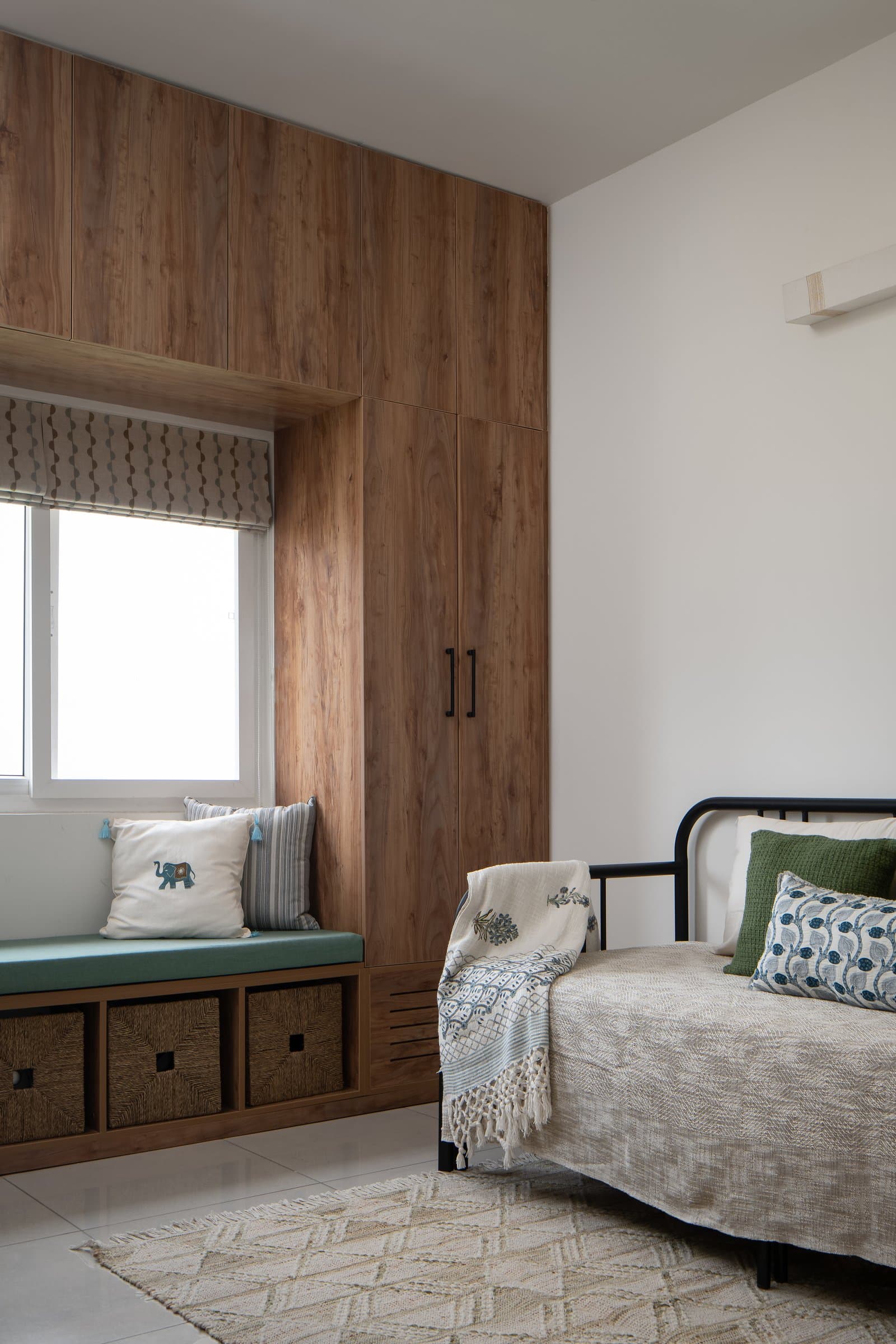 The guest bedroom, planned around a window seat with woven storage and a metal-framed daybed