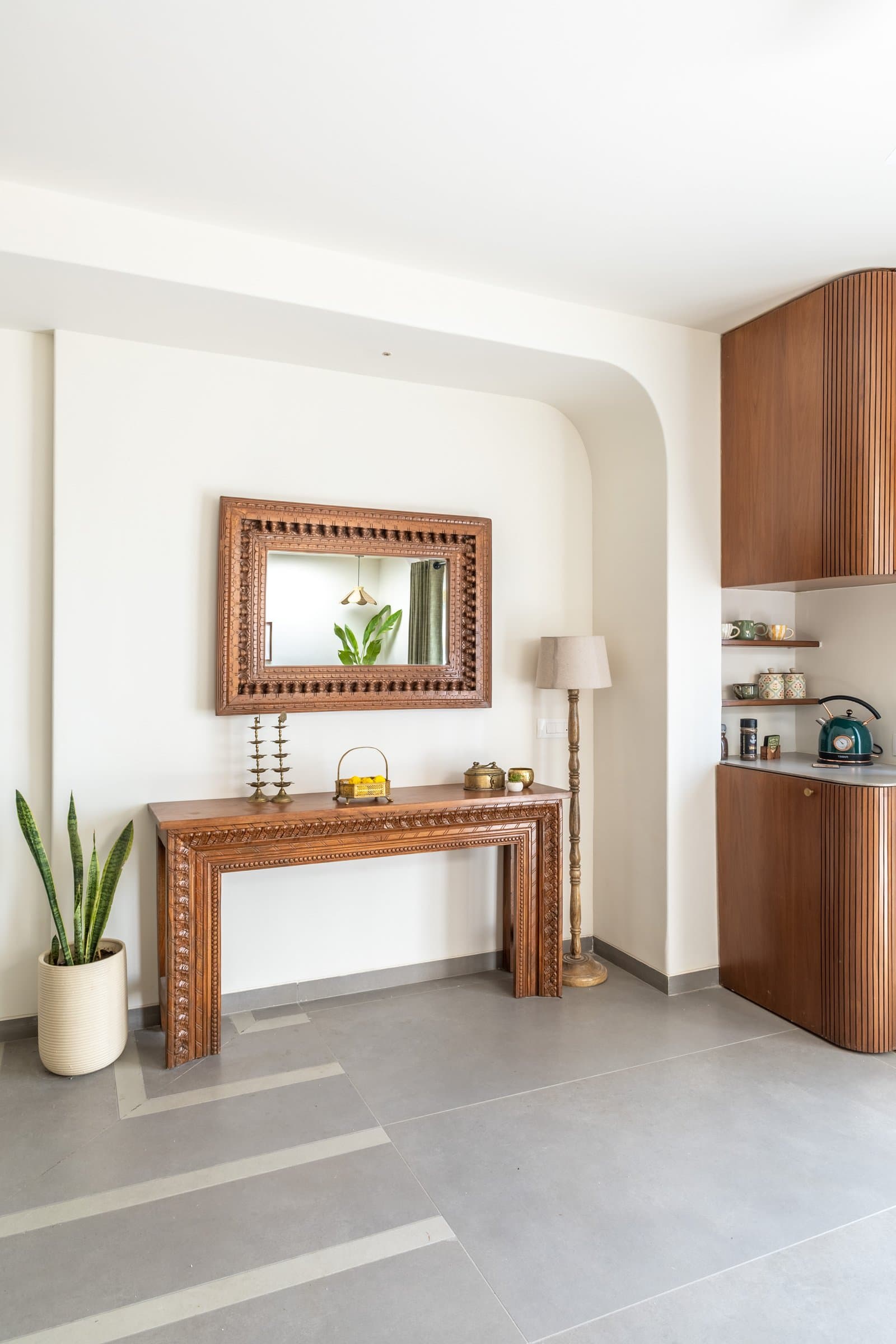 The foyer, where a carved wooden console and mirror set the home's material register before the plan unfolds